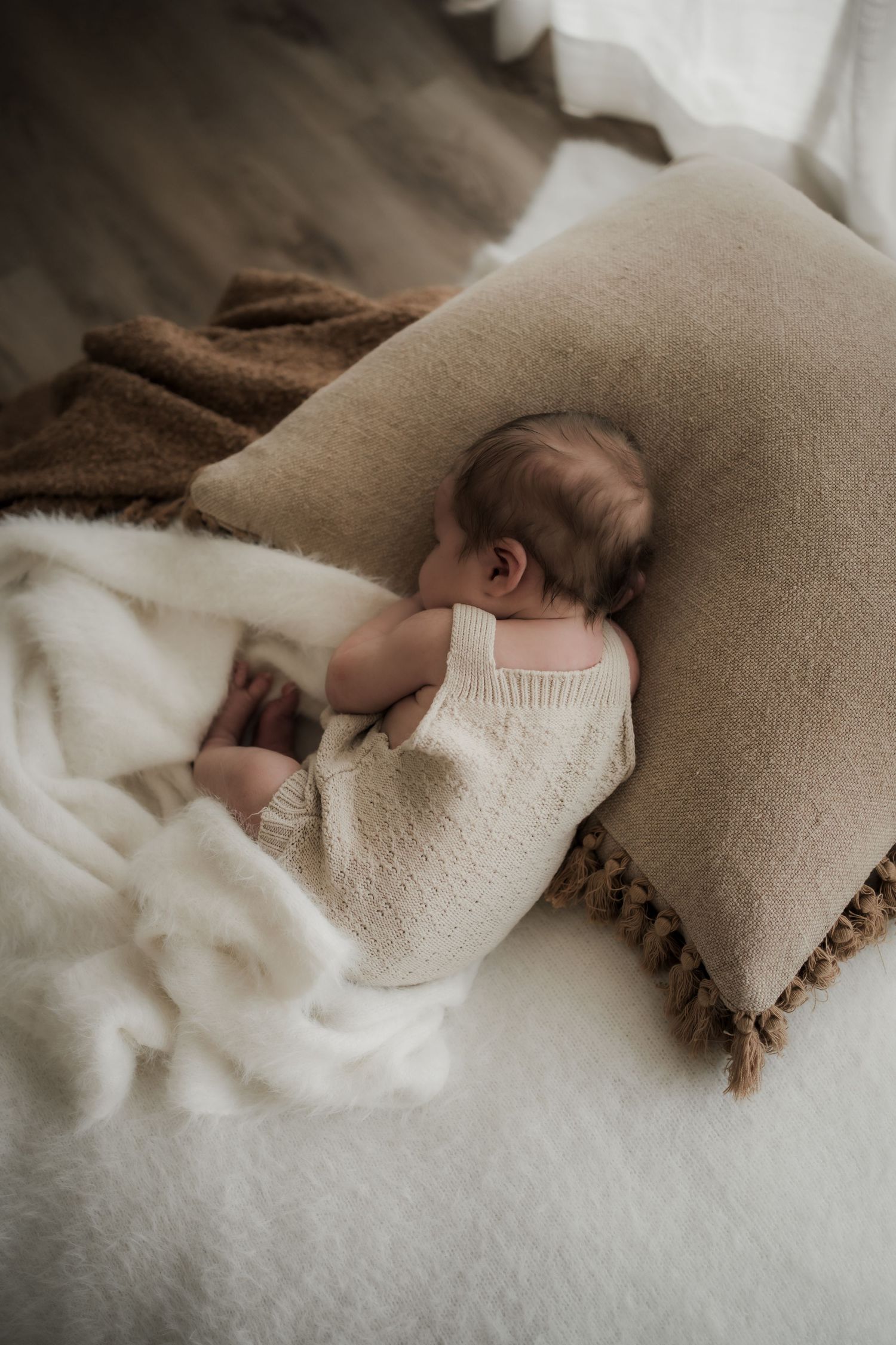 A series of cozy beige and white blankets layered together create a soft, dreamy textured backdrop.