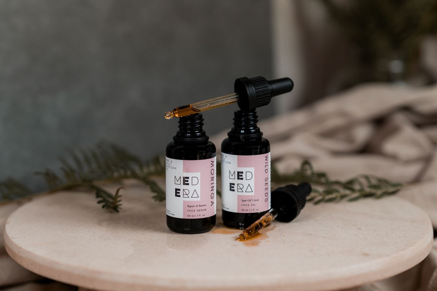 Dark glass dropper bottles with herbal tinctures arranged on a marble surface with dried botanical elements.