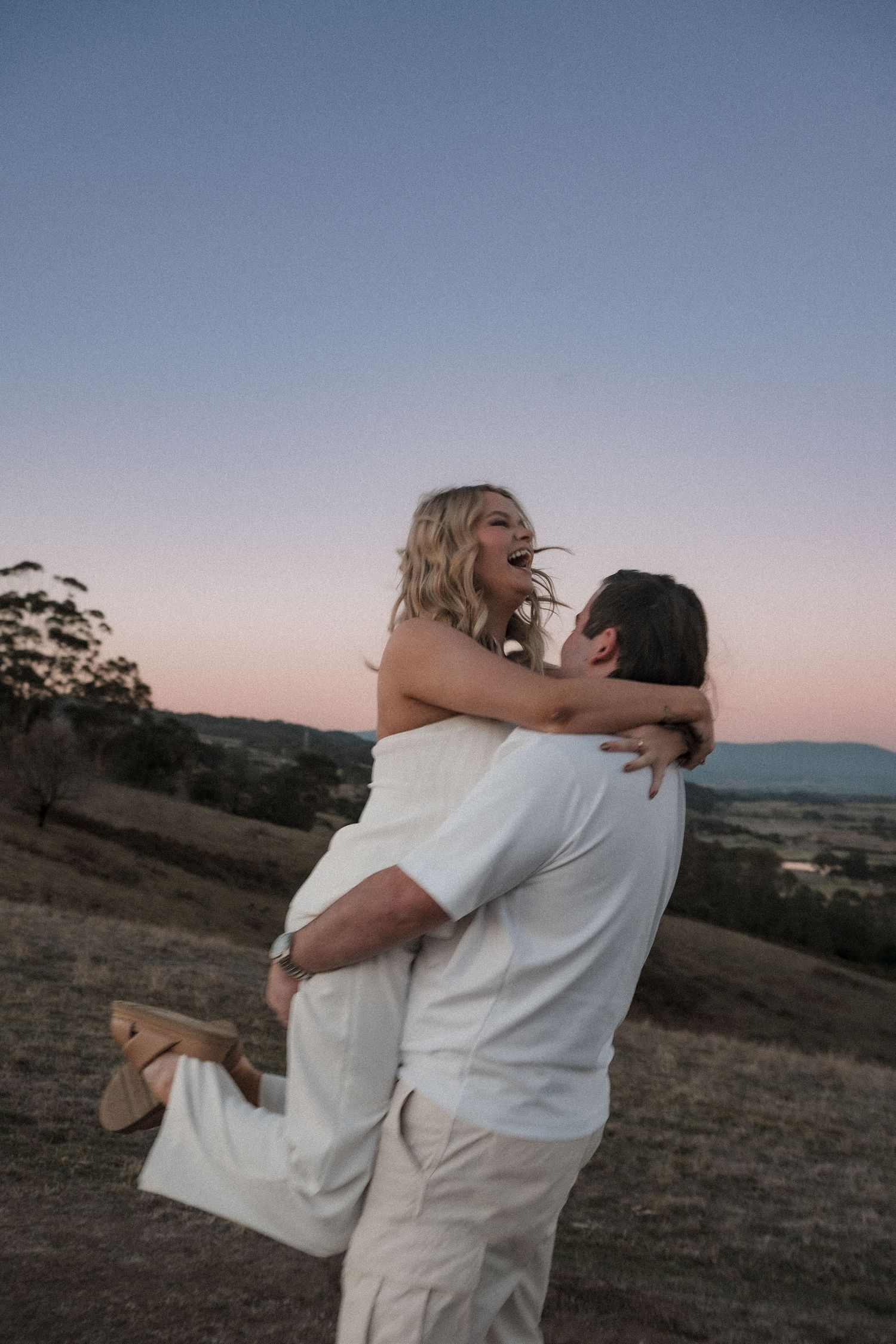 A couple embraces joyfully in a series of candid sunset photos on a hillside, captured in warm evening light.