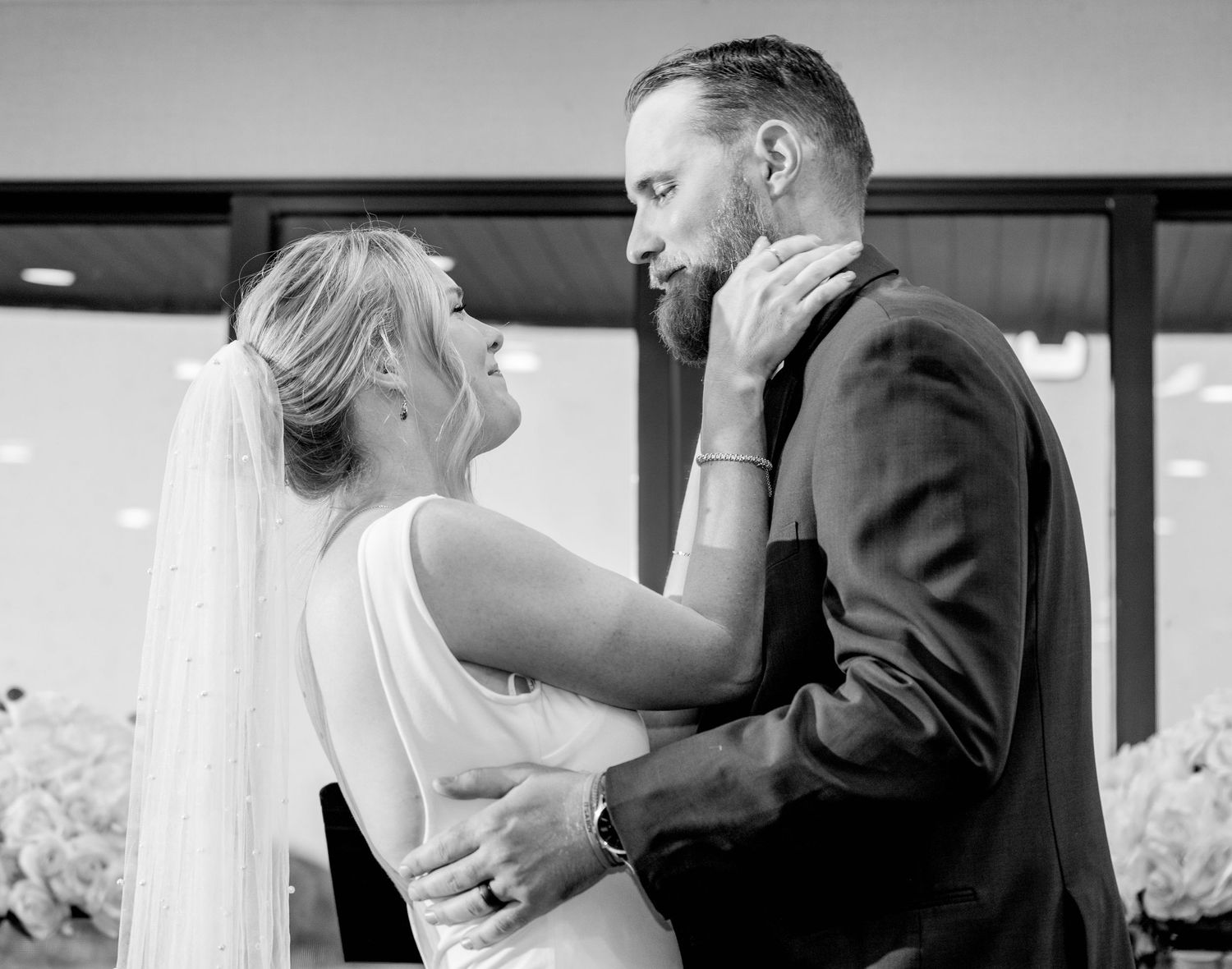 A tender black and white wedding moment captured as a bride and groom share an intimate embrace at wedding venue on boat.