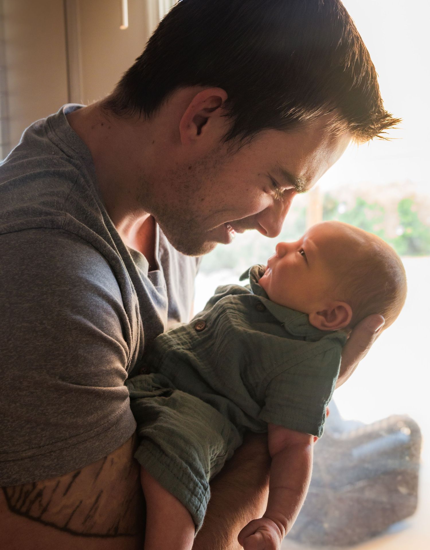 A parent and child share a tender moment together in silhouette against a bright window.