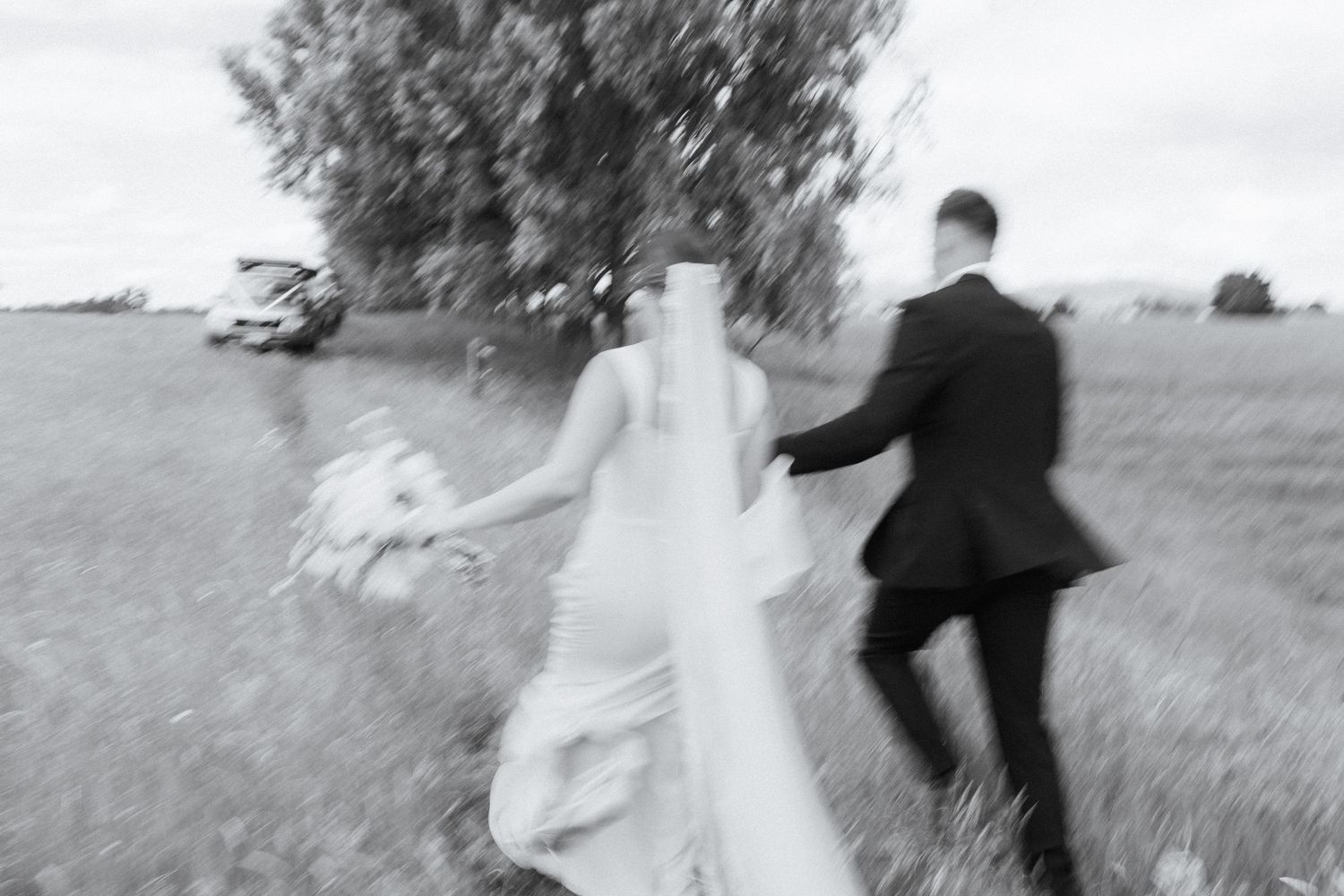 A black and white photo series showing a couple running playfully through a grassy field.