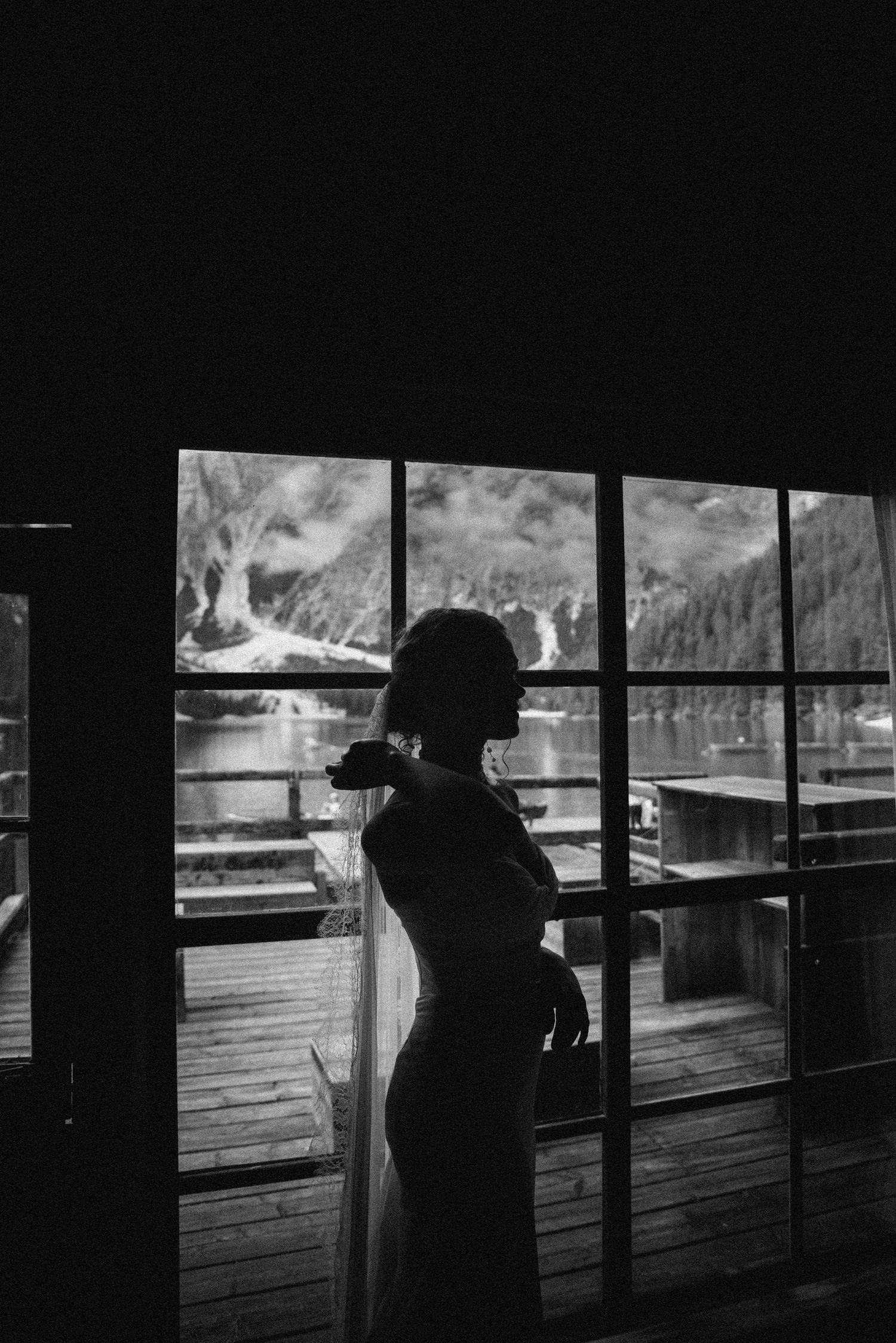 Bride silhouetted against window overlooking misty mountains in Queenstown - cinematic fine-art wedding photography.