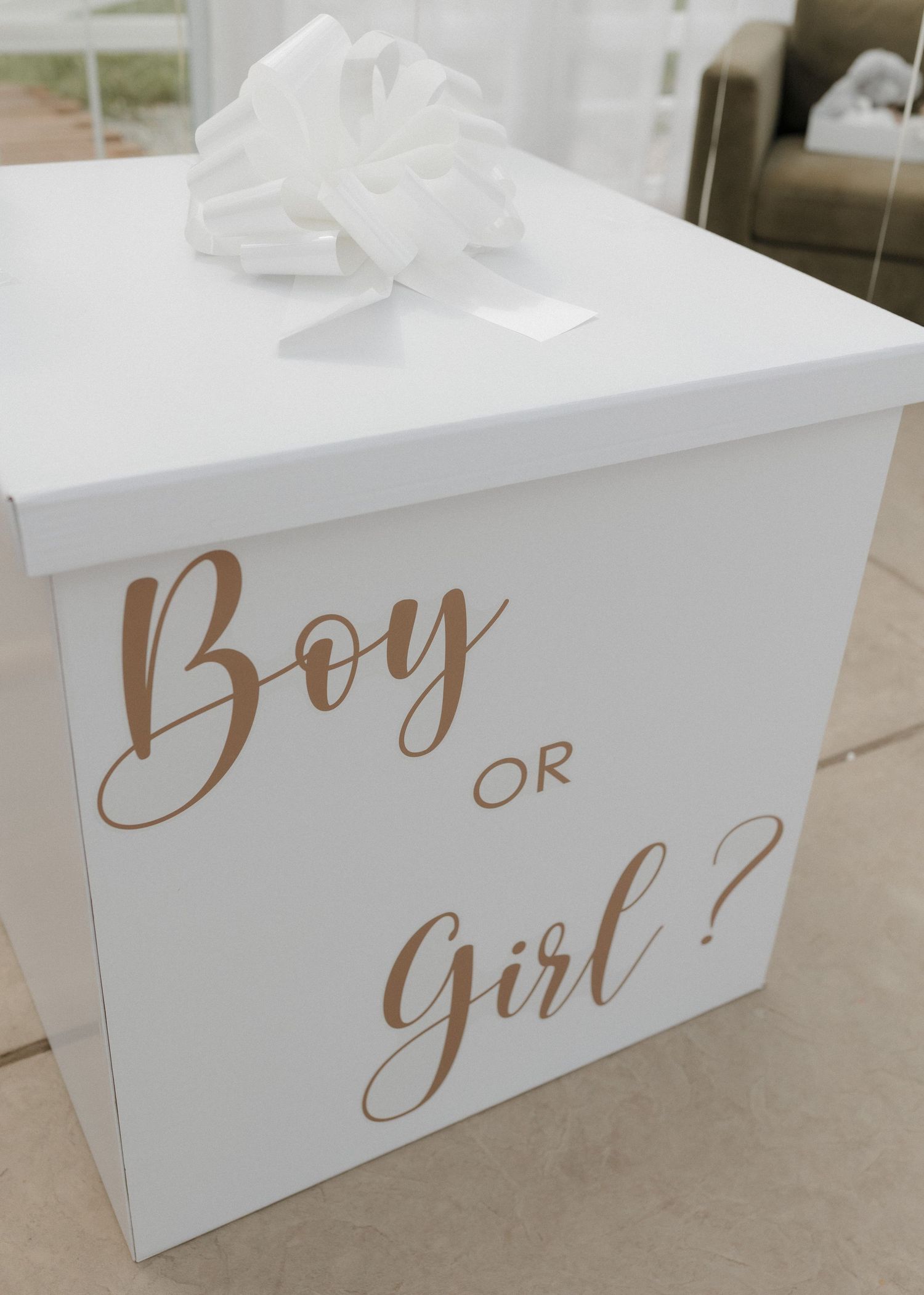 White decorative box with rose gold lettering reading 'Boy or Girl?' and white bow on top for gender reveal party decor.