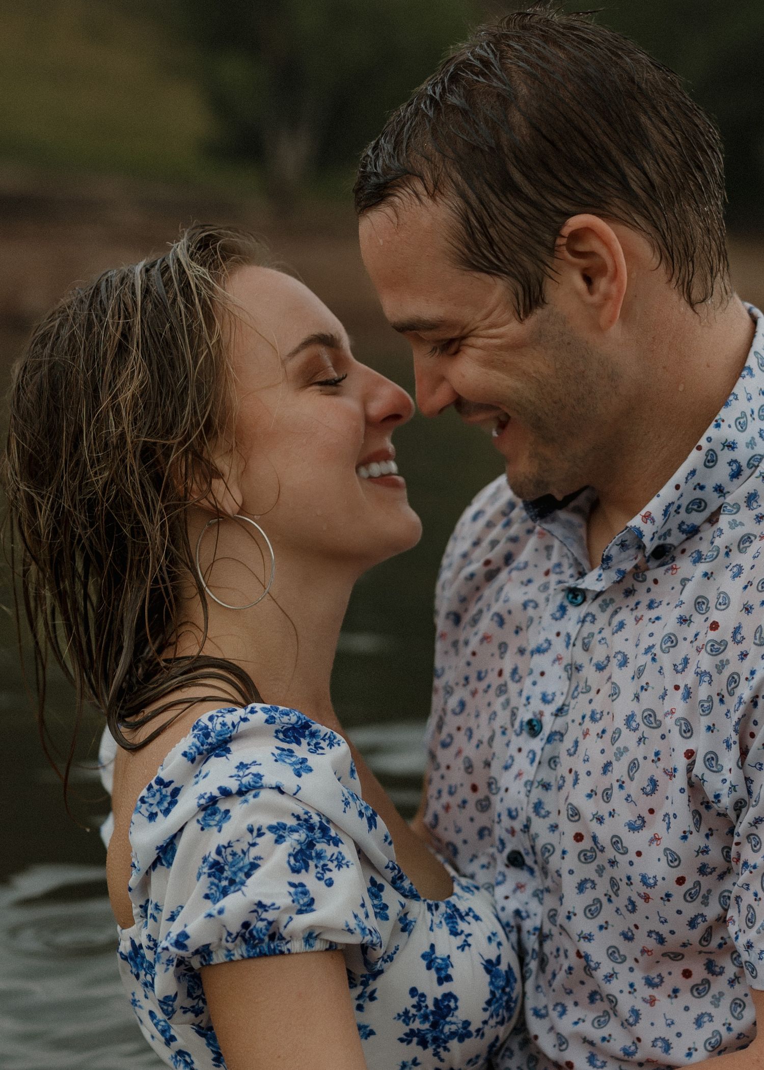 A couple shares an intimate moment by the water wearing matching floral patterned outfits.