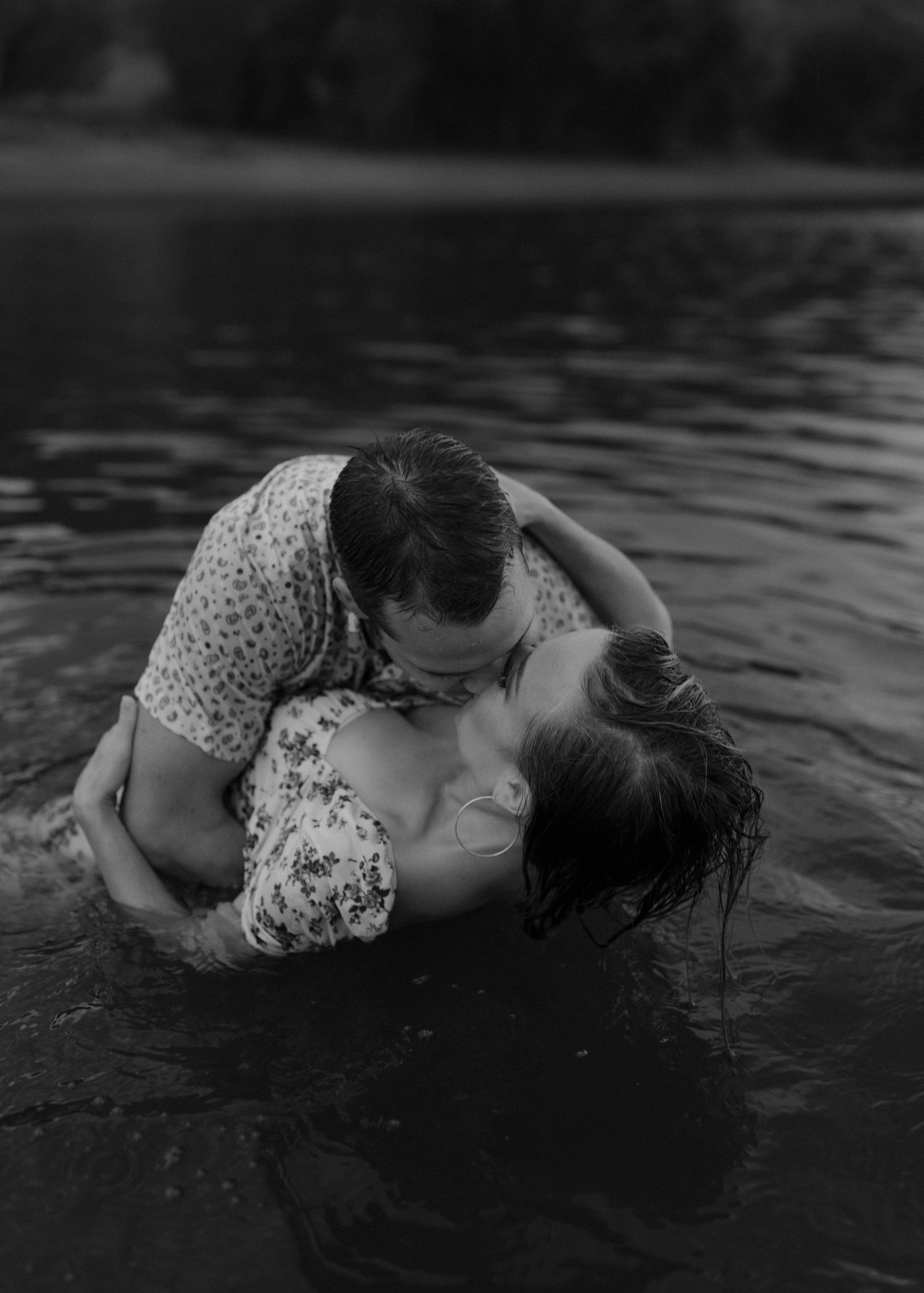 Dark artistic composition of a person floating in murky water wearing a floral patterned dress.