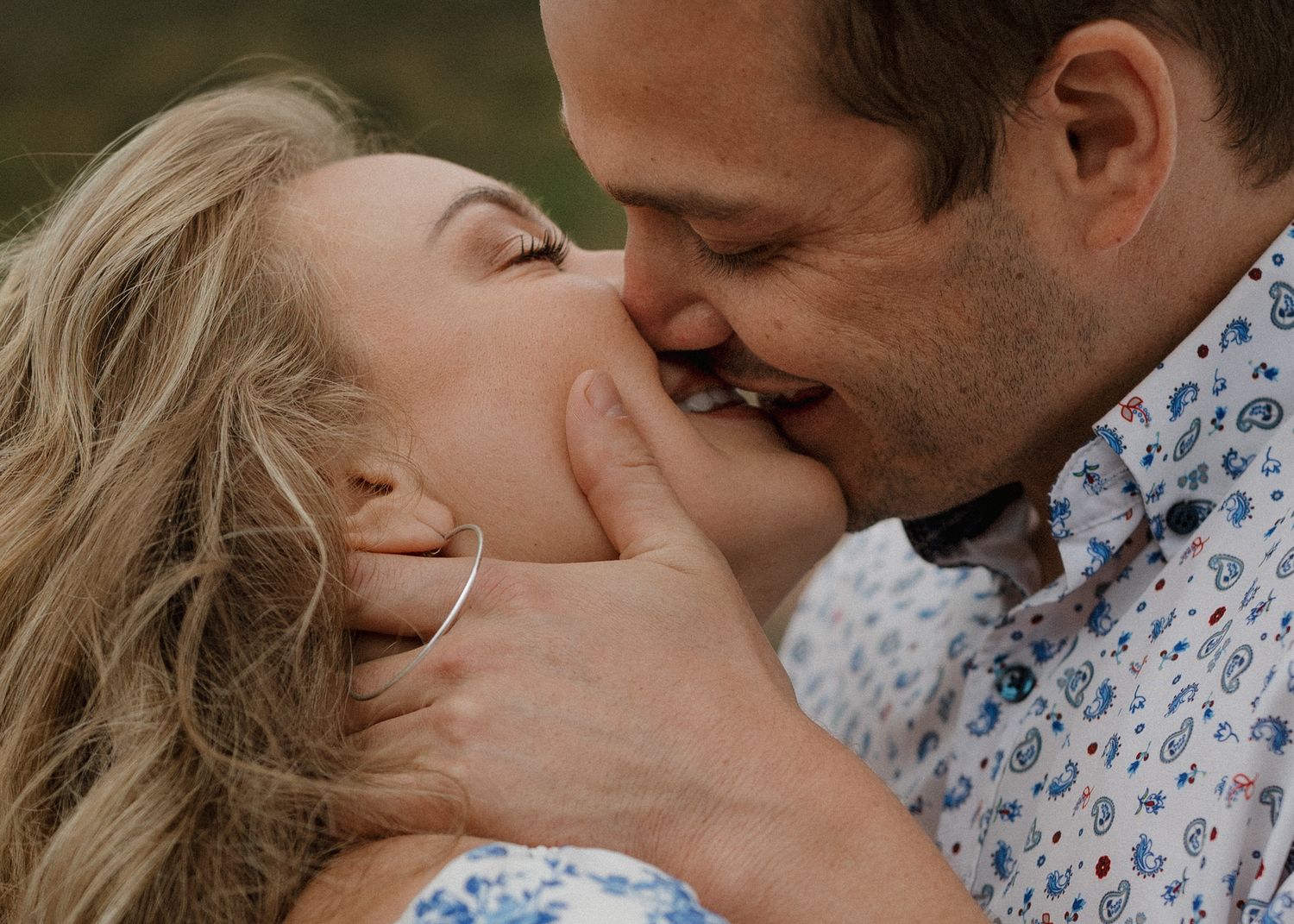 A romantic close-up moment between a couple in floral print clothing sharing an intimate kiss.