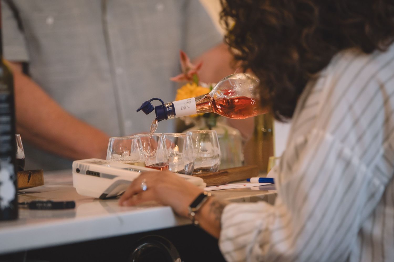 People enjoying wine and conversation at a restaurant dinner table with white tablecloth and glassware.