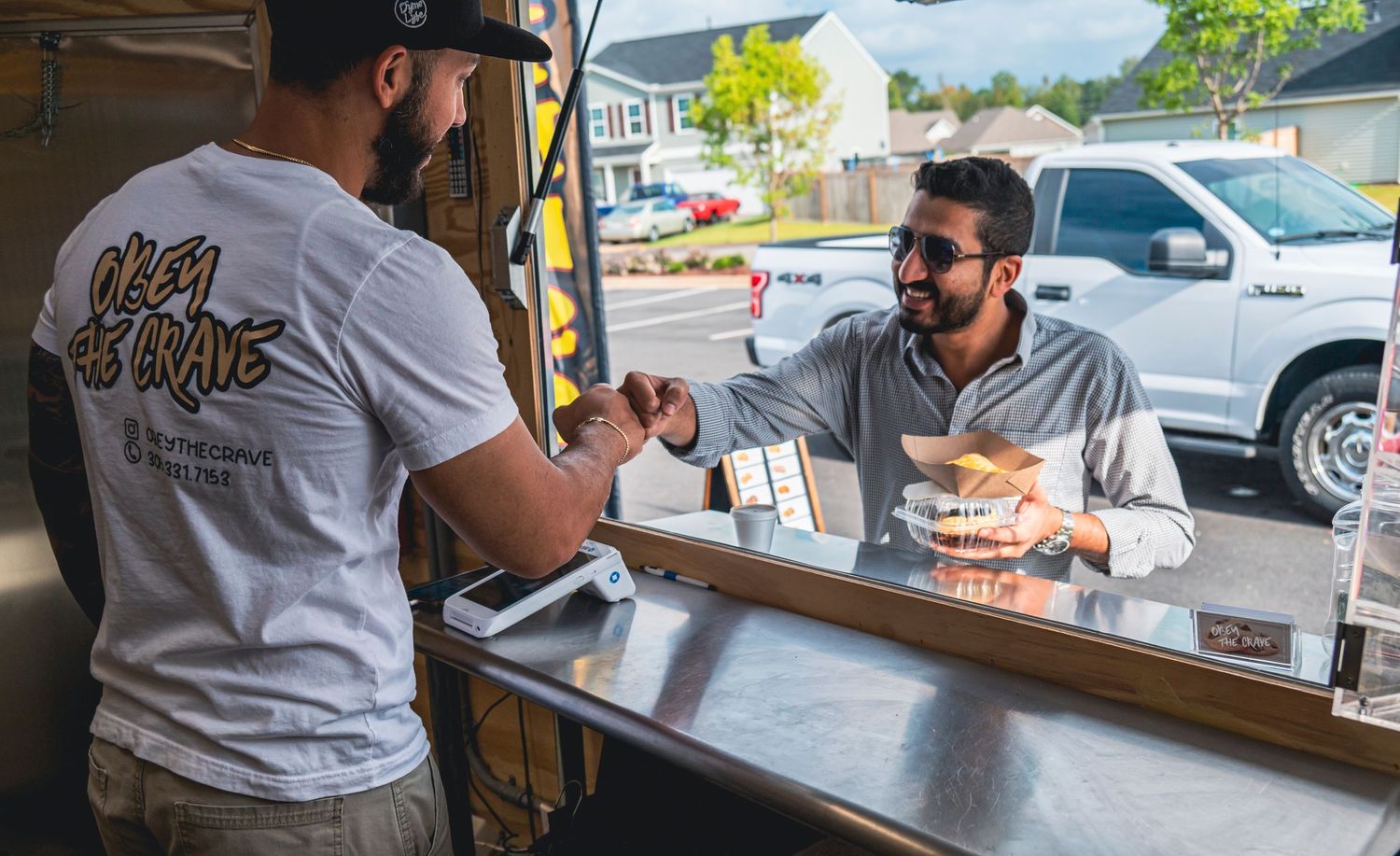 Two people chatting across a counter at a food establishment.
