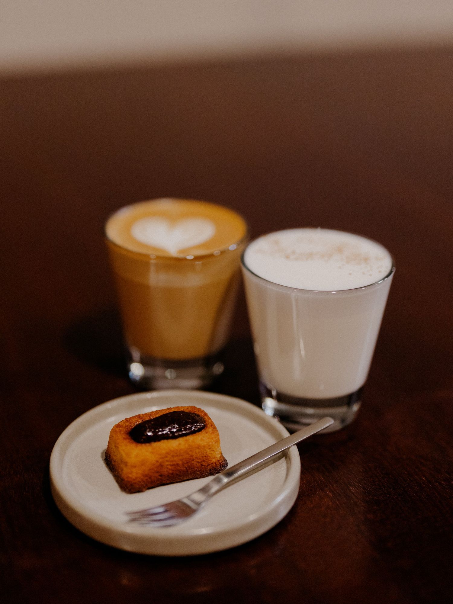 A sequence of coffee cups with latte art and pastries on white plates shown in varying angles and lighting conditions.