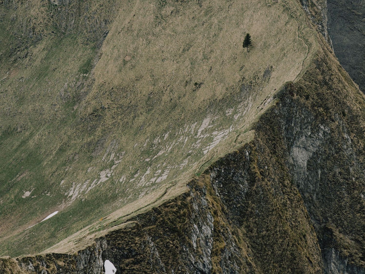Aerial view of a rugged mountain slope with barren terrain and rocky outcrops in the wilderness.