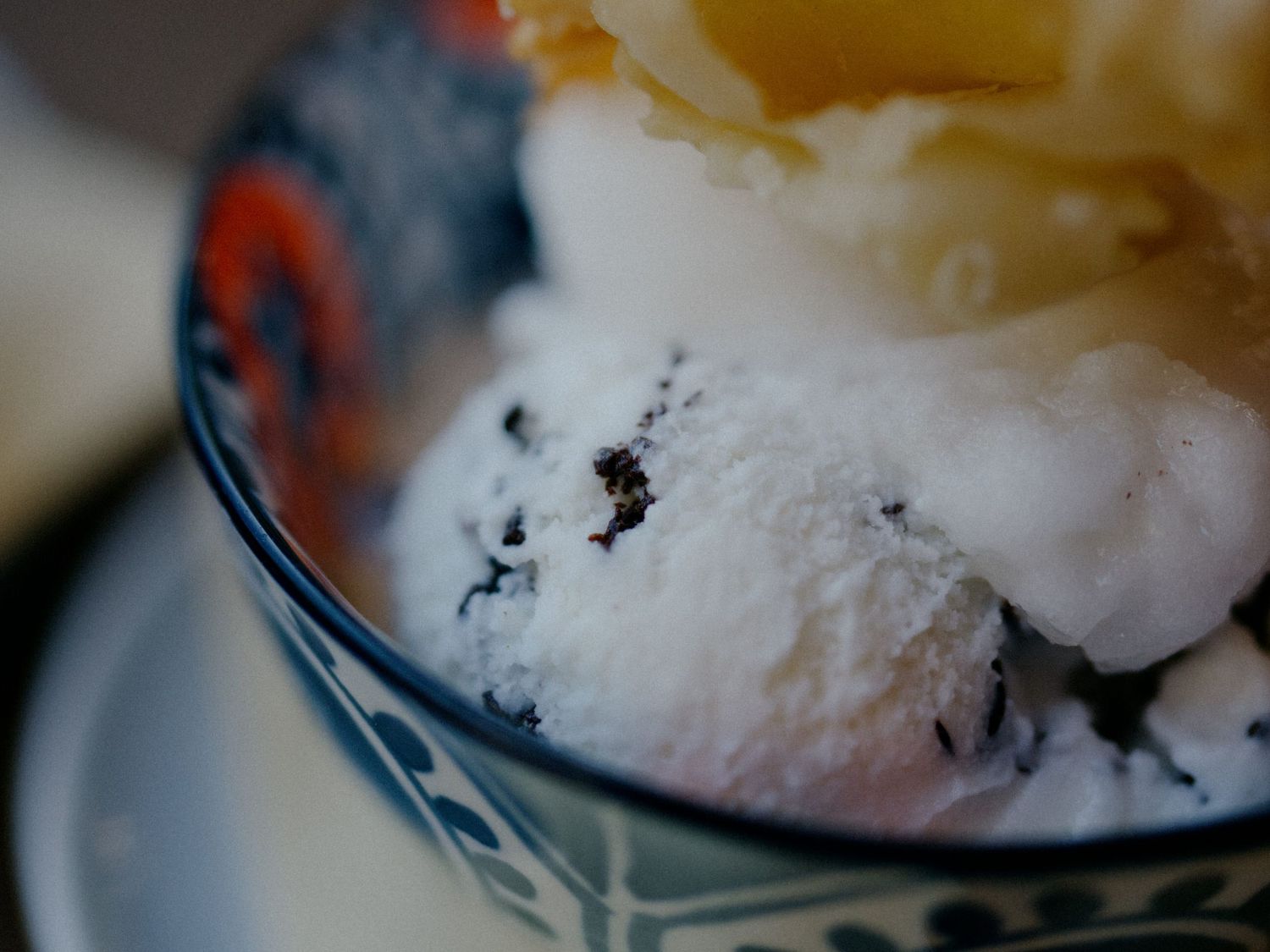 A macro shot of melting vanilla ice cream with dark specks showing rich texture and creamy consistency.