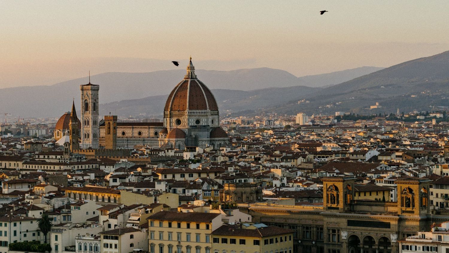 Panoramic cityscape of Florence Italy at sunset showcasing iconic Duomo cathedral and historic architecture.