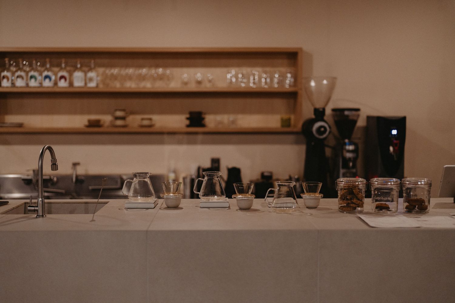 A modern coffee shop counter with pour-over equipment and brewing stations in warm sepia tones.