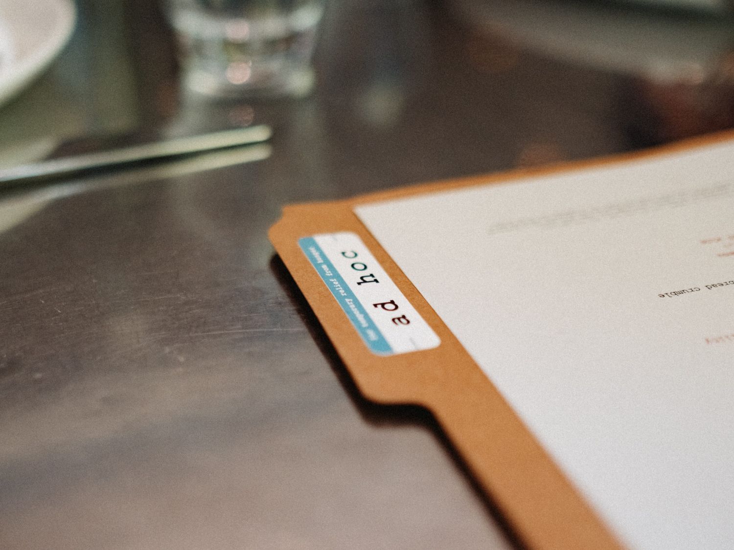 Close-up of a manila folder with a blue label reading SCOPE on a stainless steel restaurant table.