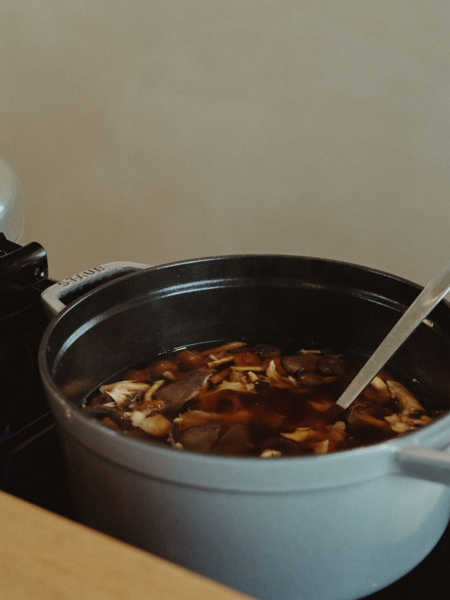 A bowl of hot soup with mushrooms and other ingredients simmering in dark broth.