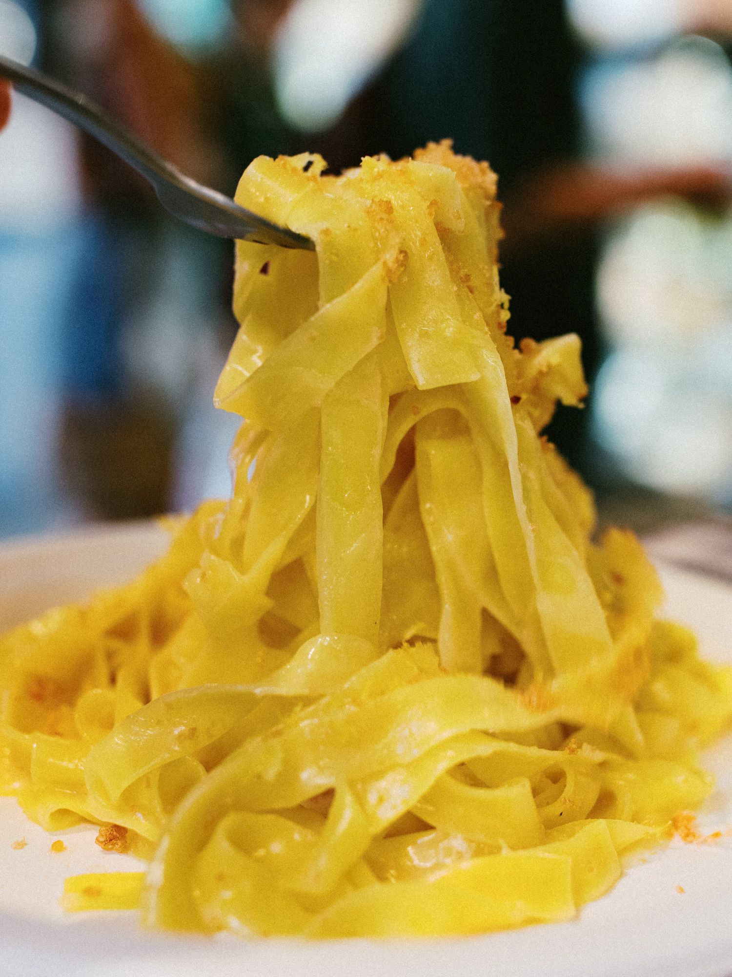 Close-up view of fresh yellow pasta ribbons arranged in delicate folds against a blurred background.