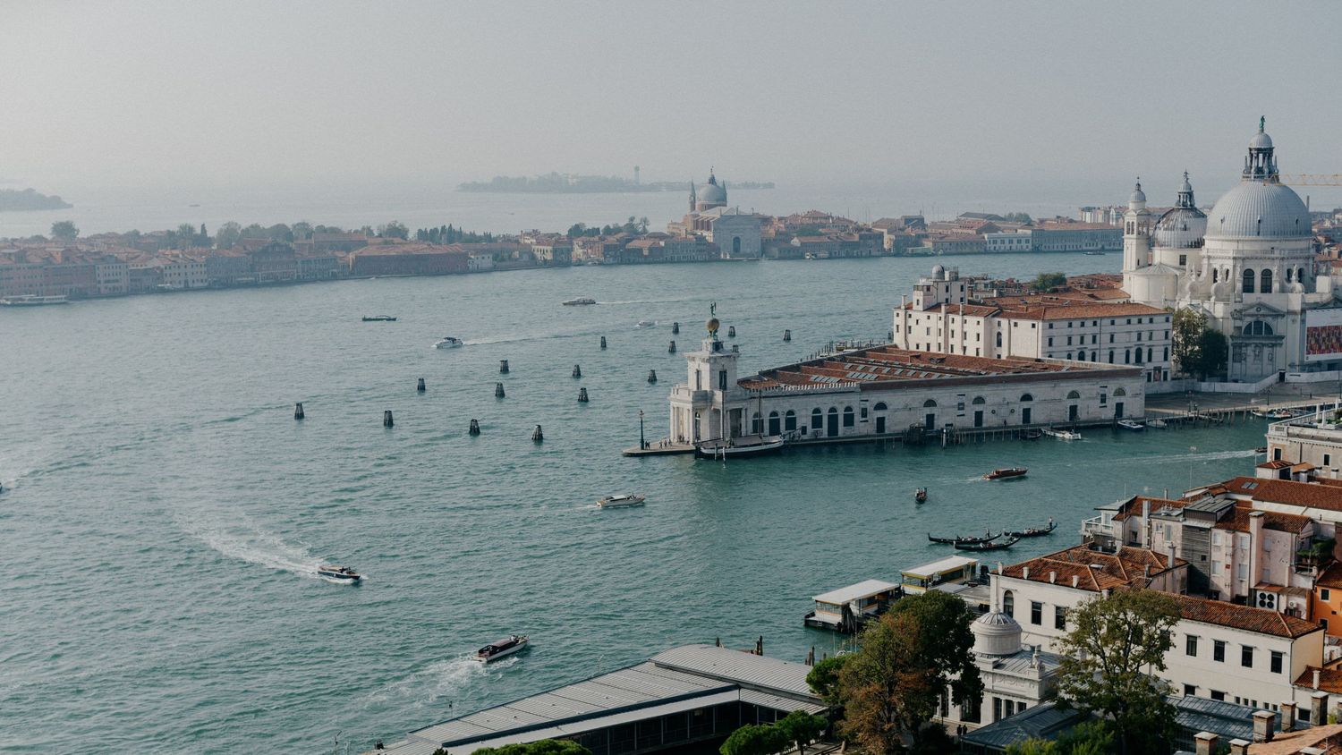 A panoramic view of Venice's Grand Canal with historic buildings and domes along the waterfront during daytime.