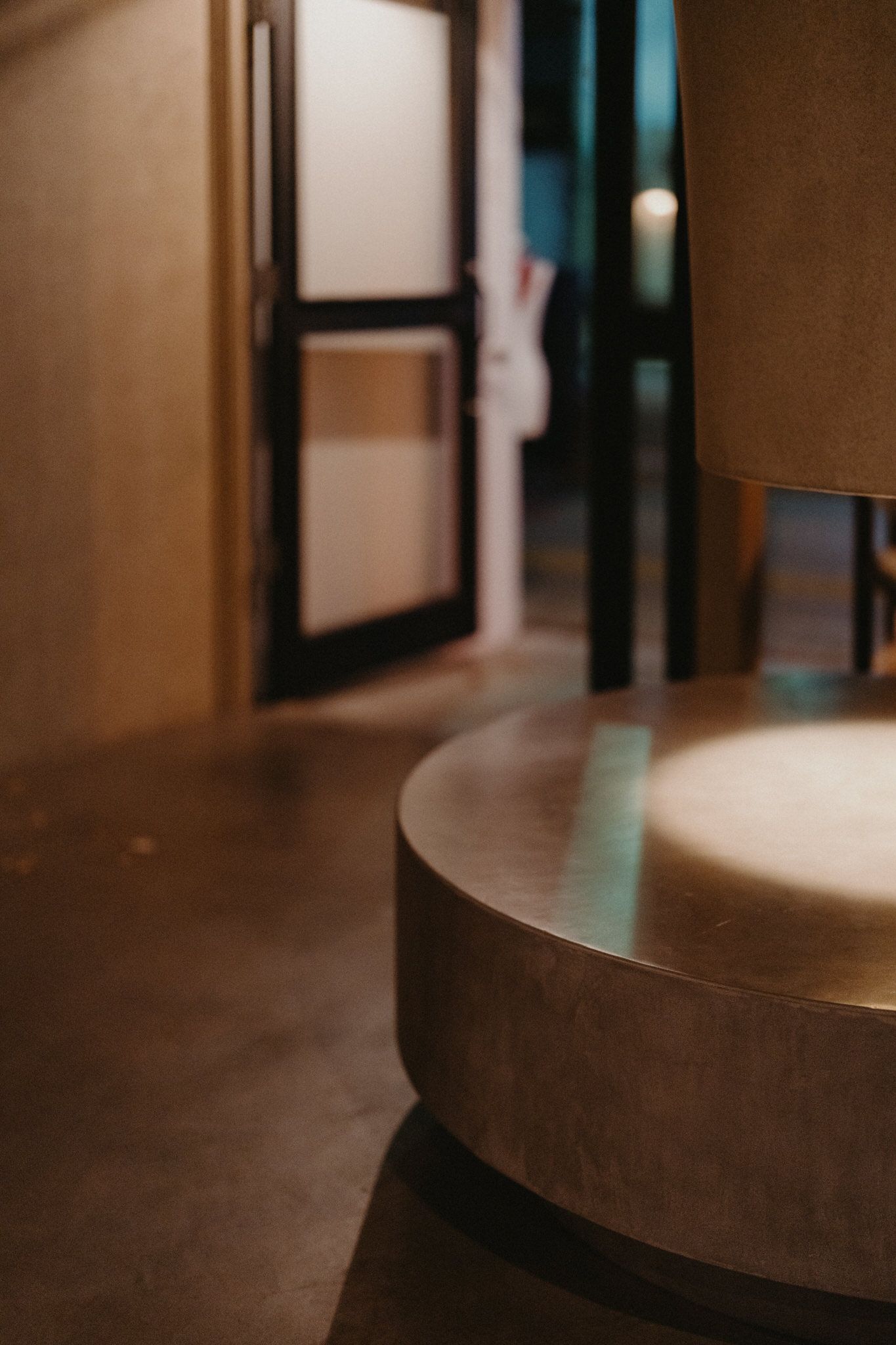 Blurred interior view showing a curved wooden table edge and doorway in warm brown tones with soft lighting.
