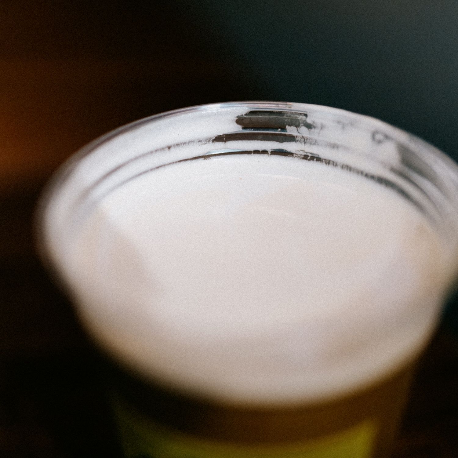 Close-up view of a glass of beer showing the white foam head gradually settling on top of the golden liquid.