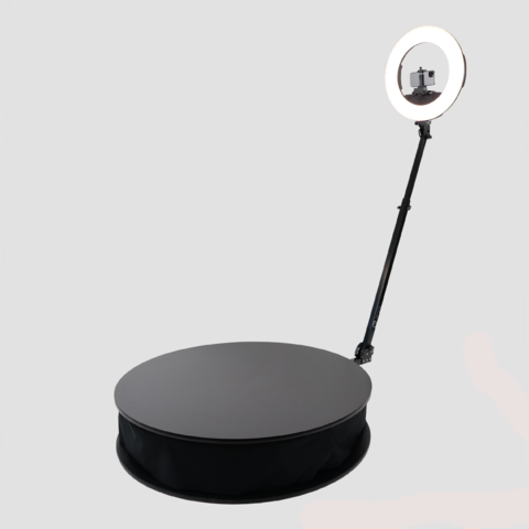 Black rotating photo booth platform with adjustable arm, ring light, and camera mount for professional photography.