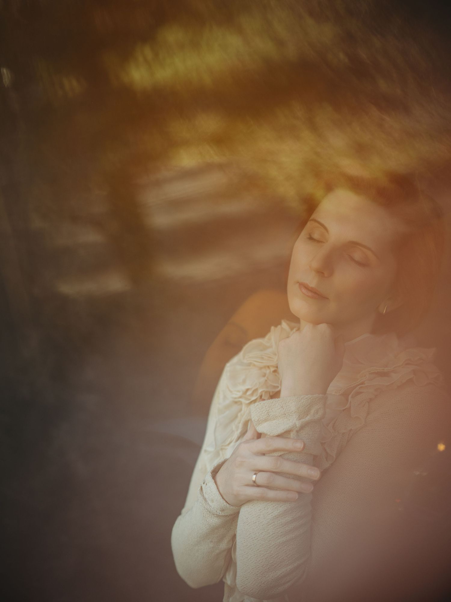 Dreamy vintage portrait in soft focus showing figure in white lace with eyes closed in ethereal lighting.