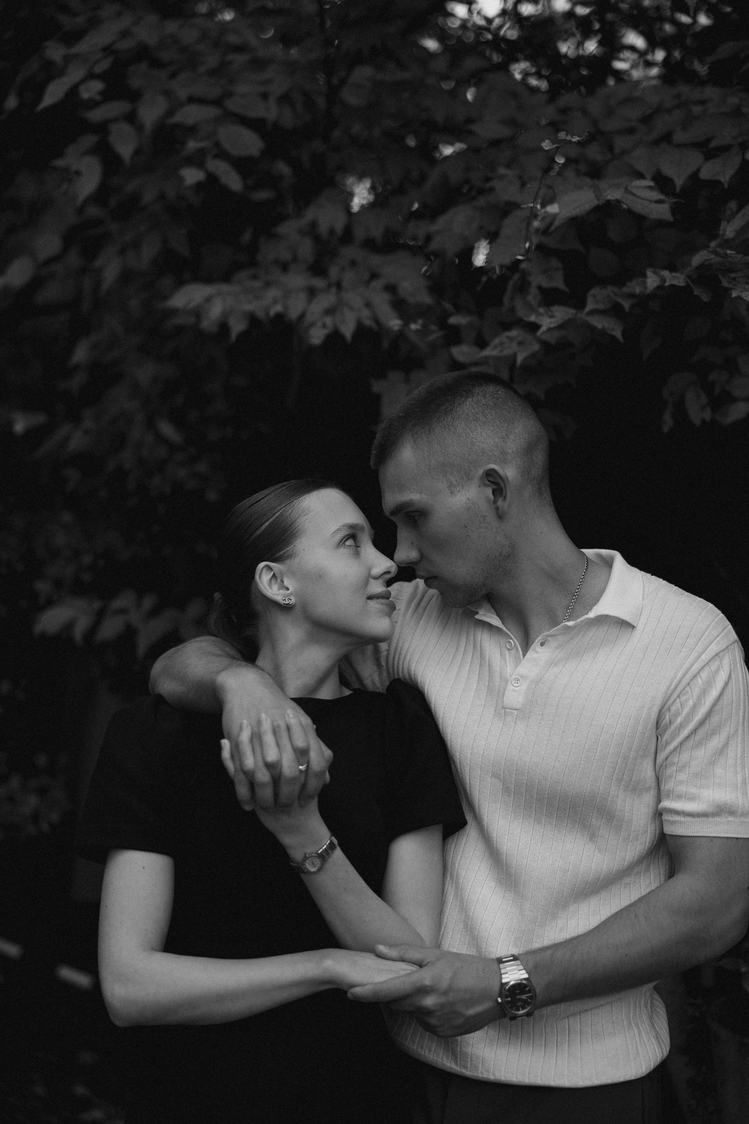 A series of black and white romantic photos showing a couple embracing and sharing intimate moments outdoors.
