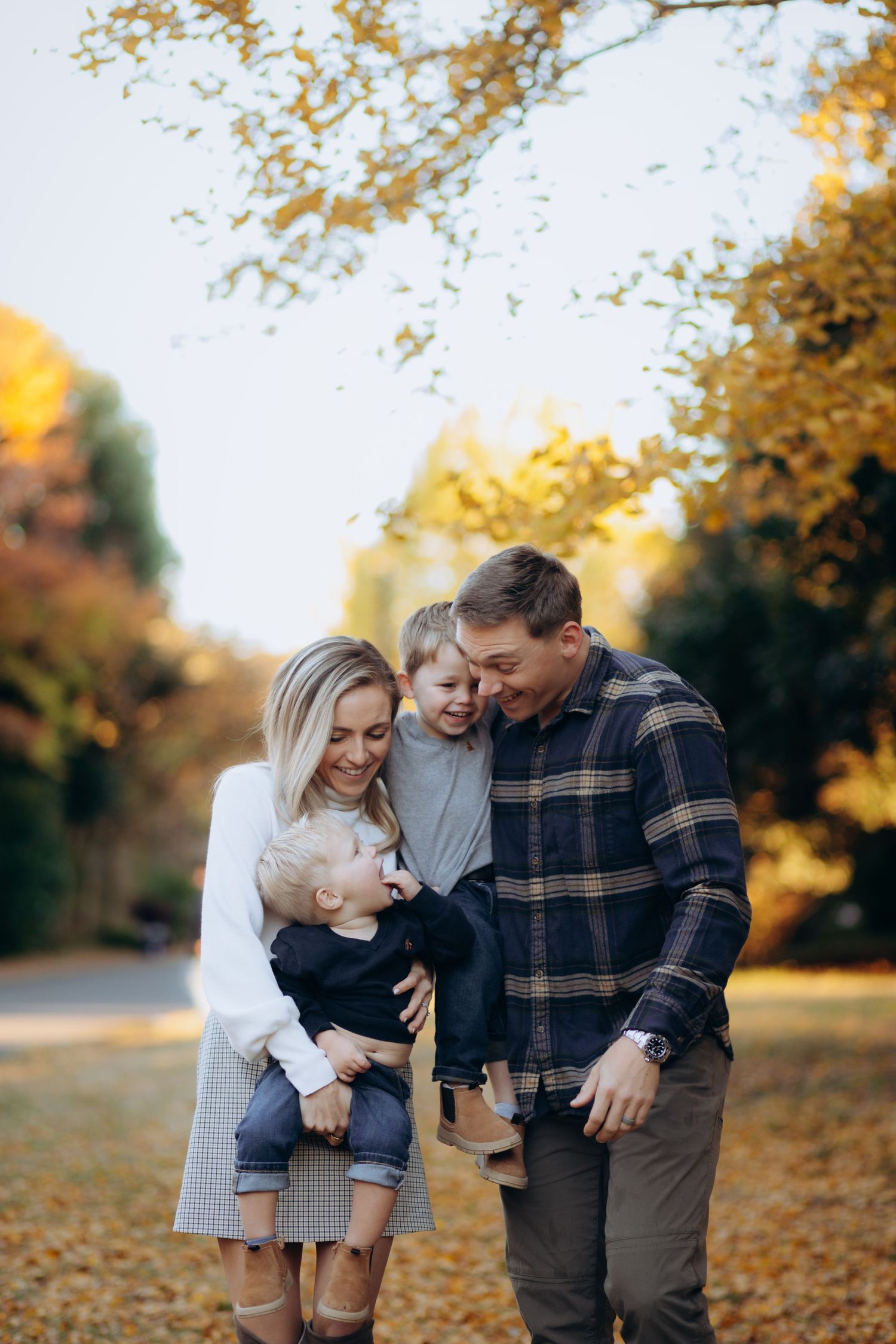 A happy group shares a candid moment together outdoors on an autumn day with golden fall foliage in the background.