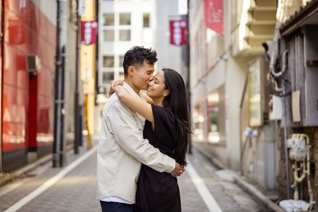 A romantic embrace in an urban alley with Japanese street signs and architecture.