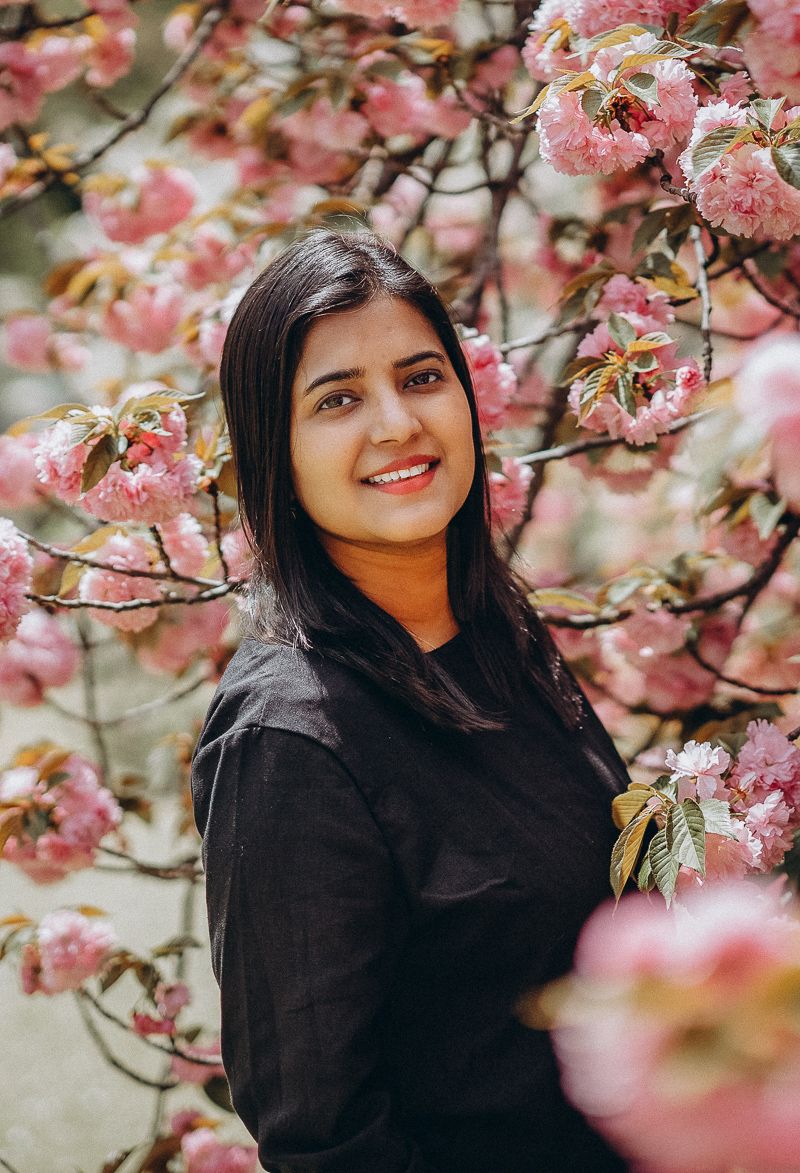 Pink cherry blossoms frame a portrait against a springtime backdrop.