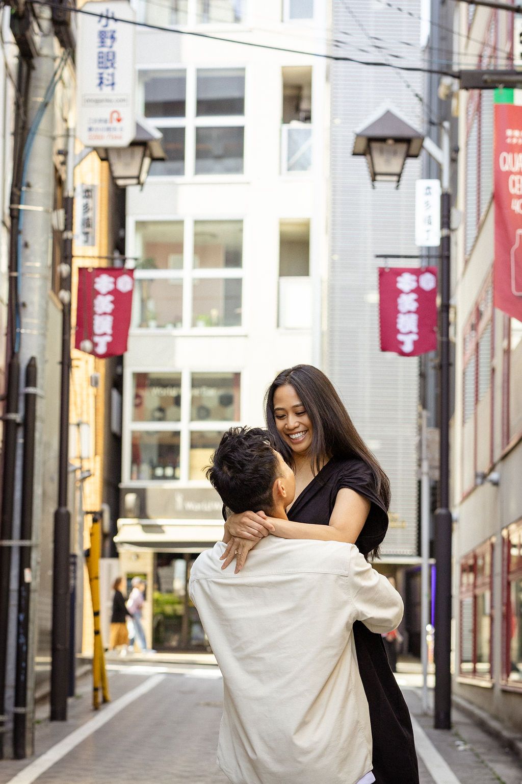 A joyful moment shared between a couple in a narrow Japanese street with lanterns.