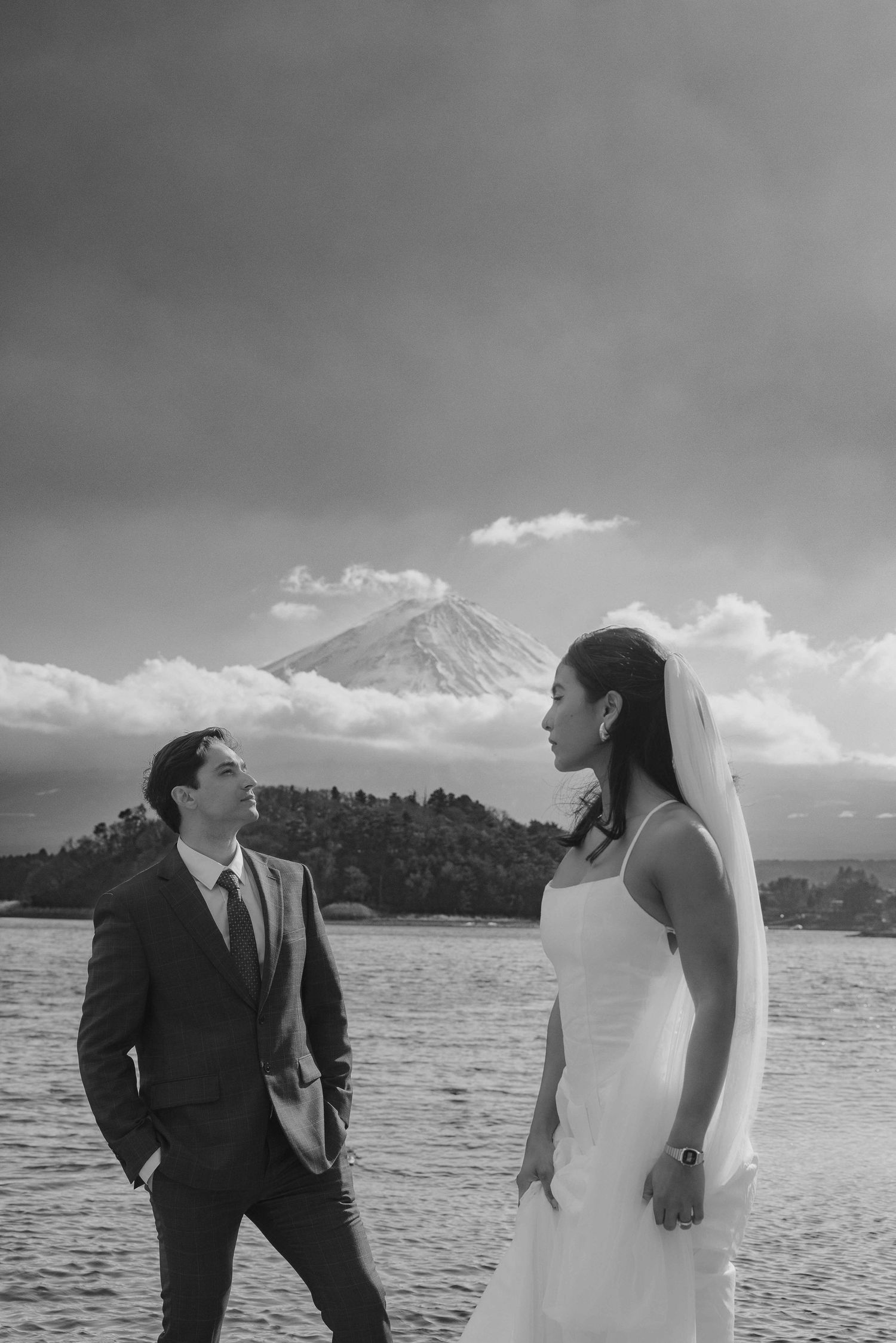 A romantic black and white wedding photoshoot on the shores of a lake with mountains in the background.