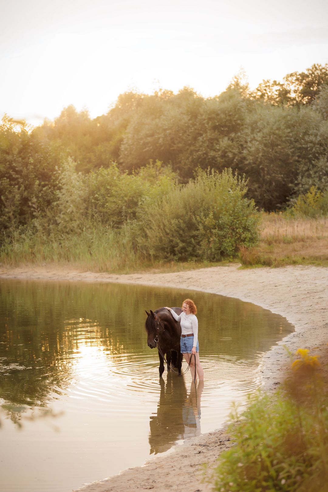 Paard en eigenaar staan in water tijdens golden hour fotoshoot
