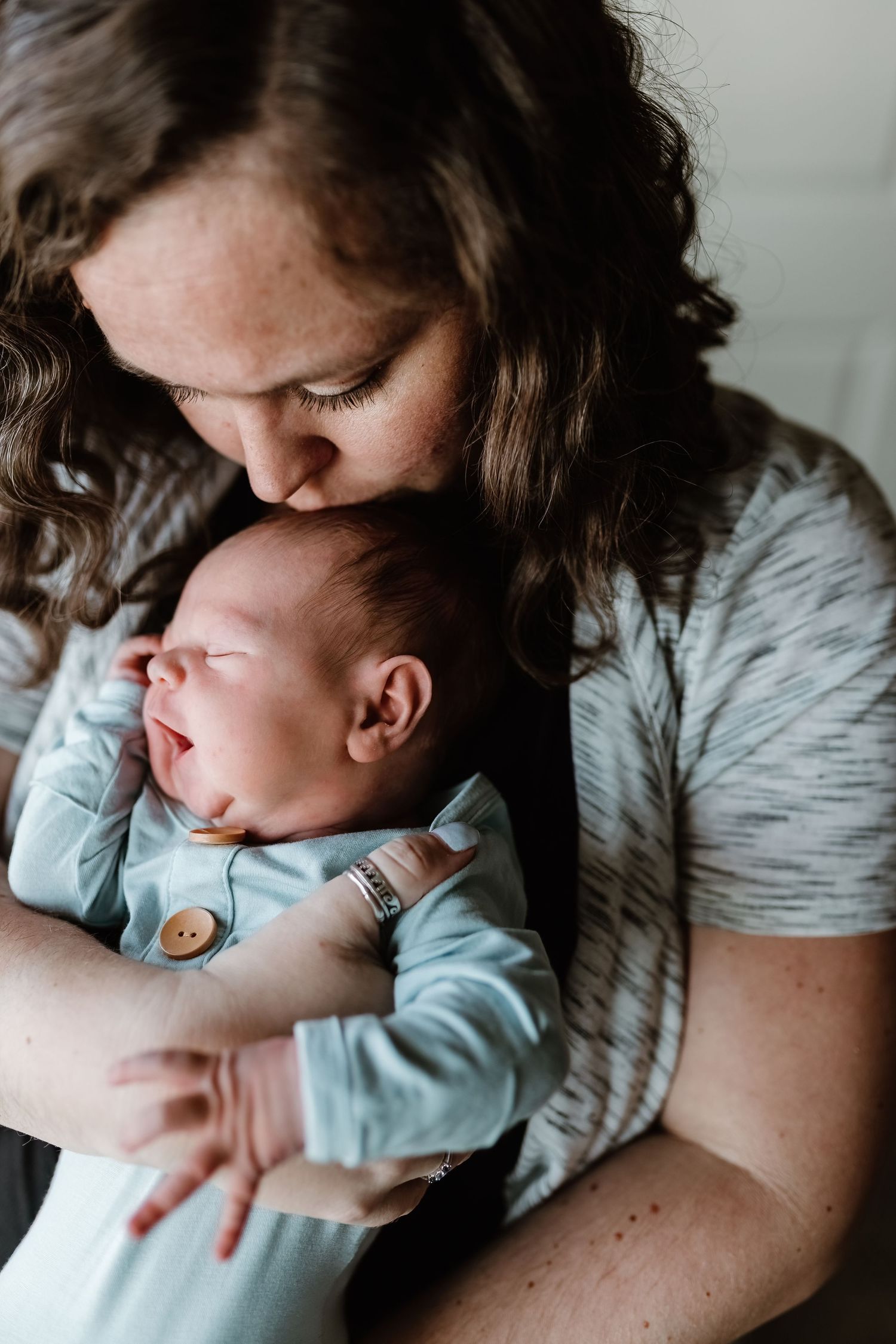 A tender moment between parent and newborn baby in soft, intimate lighting.