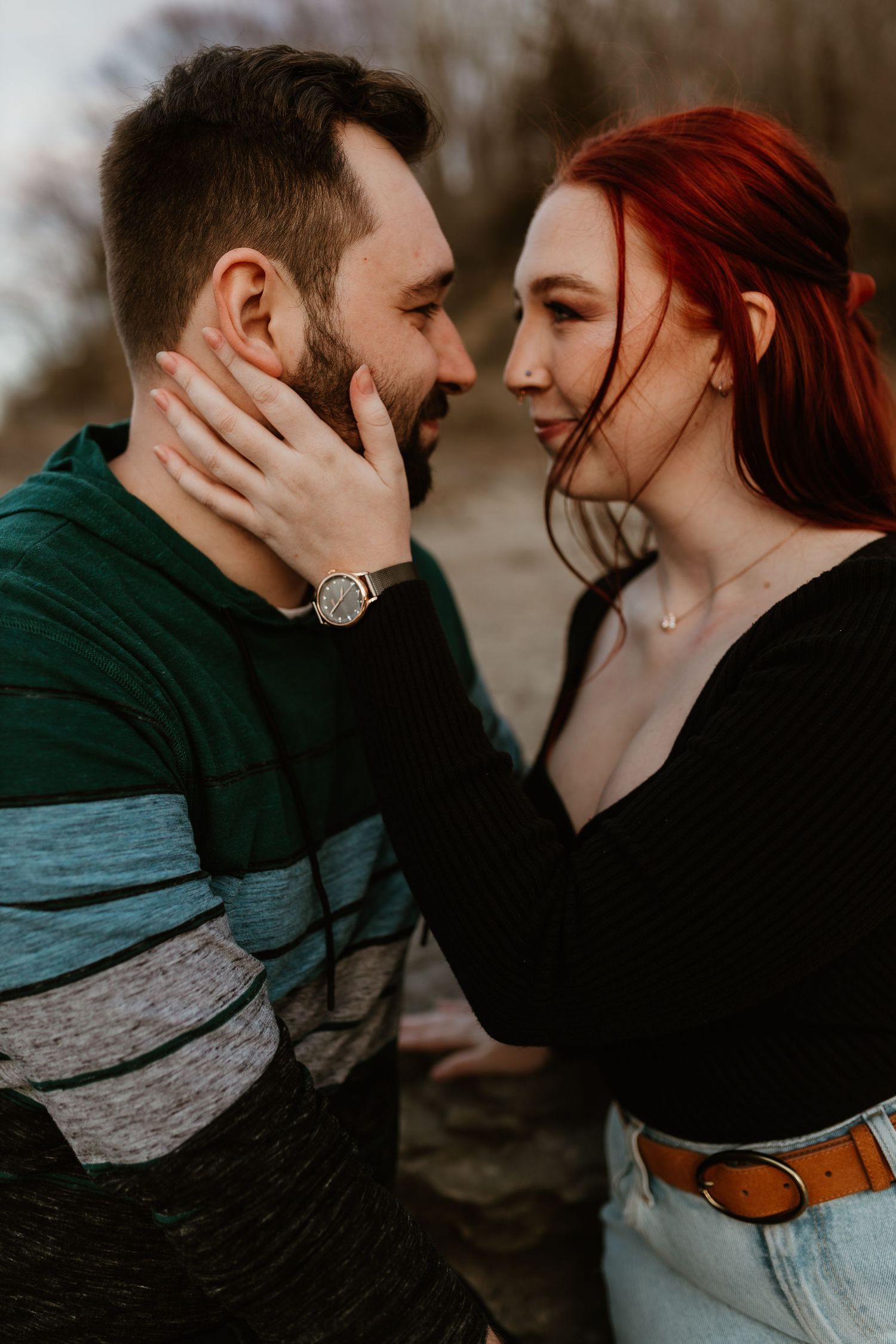 A romantic close-up photo of a couple sharing an intimate moment outside.