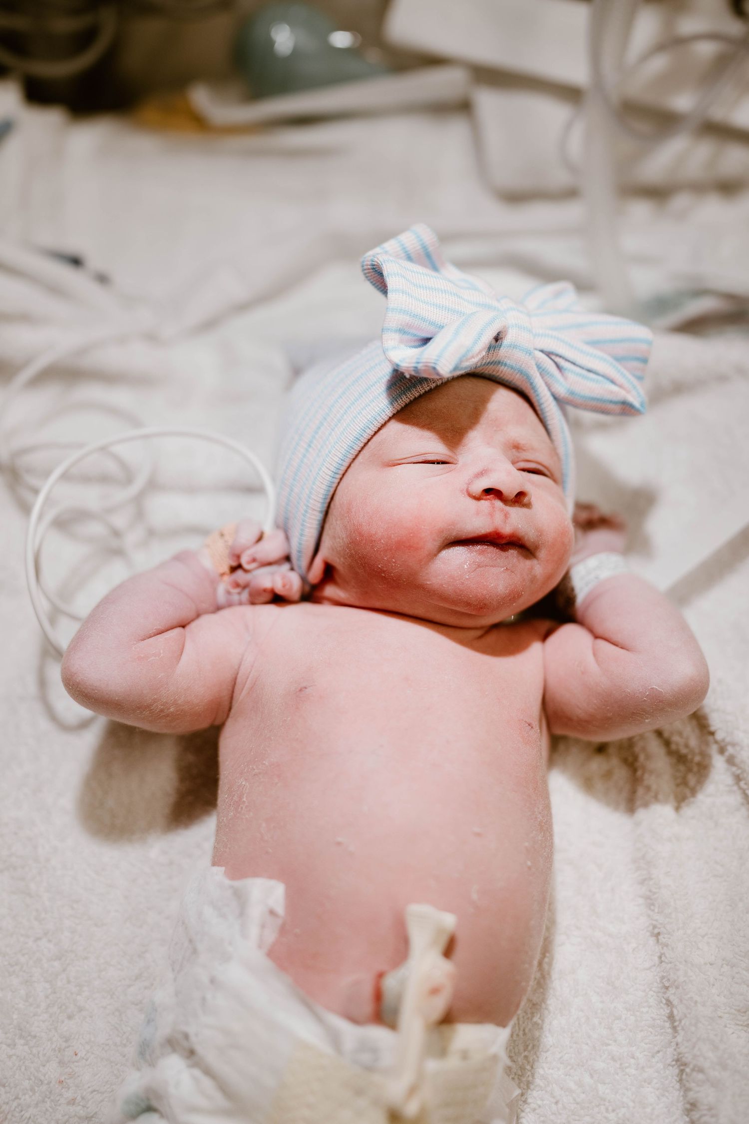 A sleeping newborn baby wrapped in white blankets lies peacefully on soft bedding.