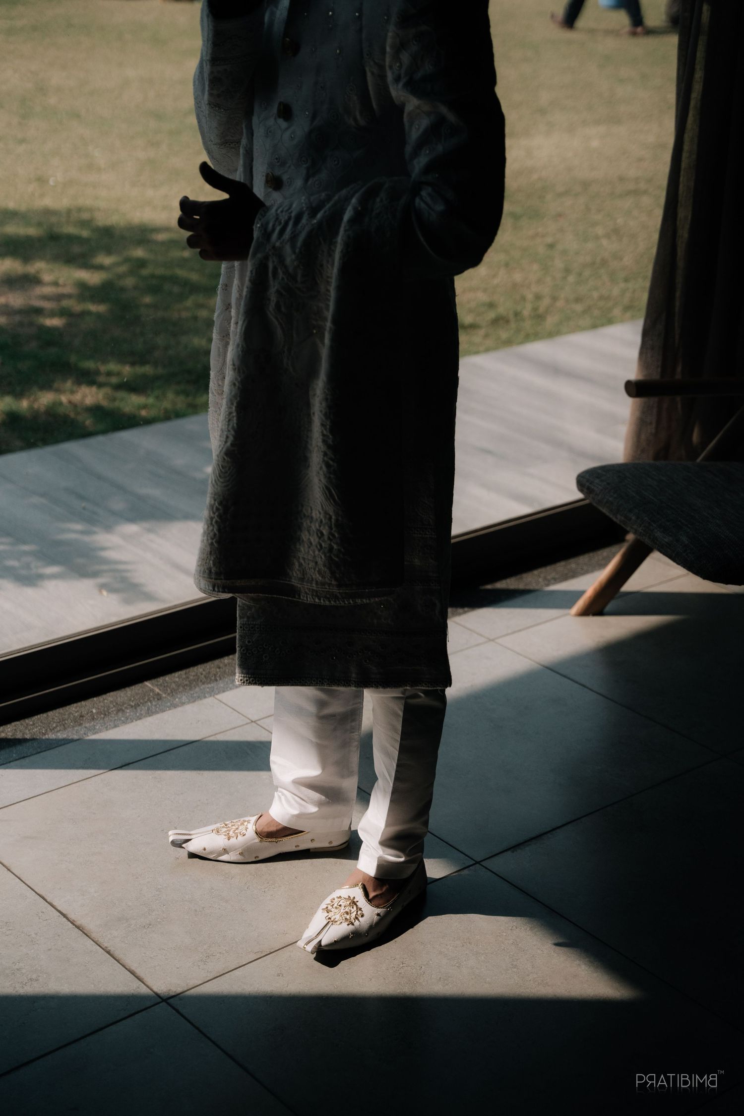 Low angle view of traditional formal attire and oxford shoes on tiled floor.