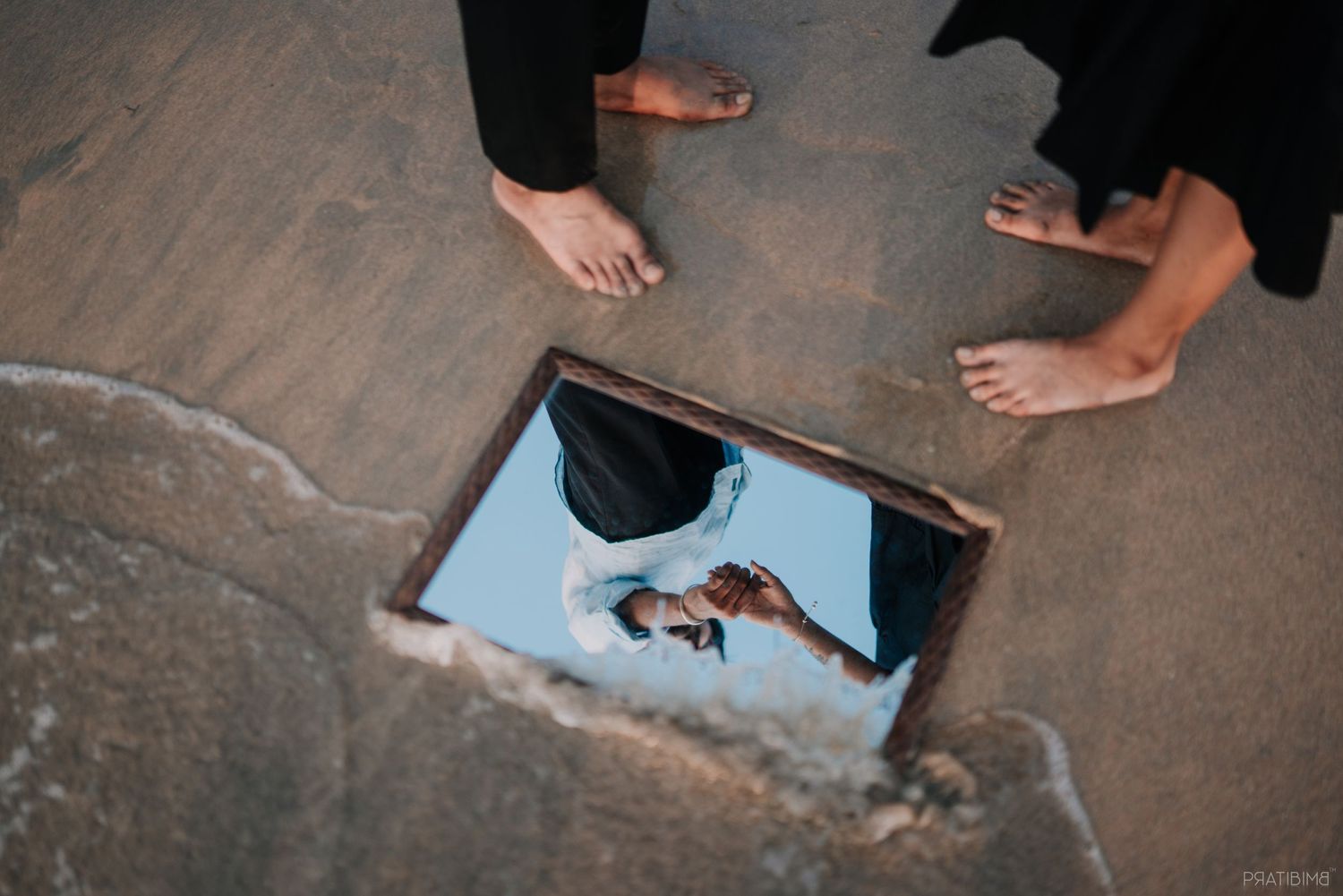 Bare feet stand around a reflective surface displaying a romantic photograph.