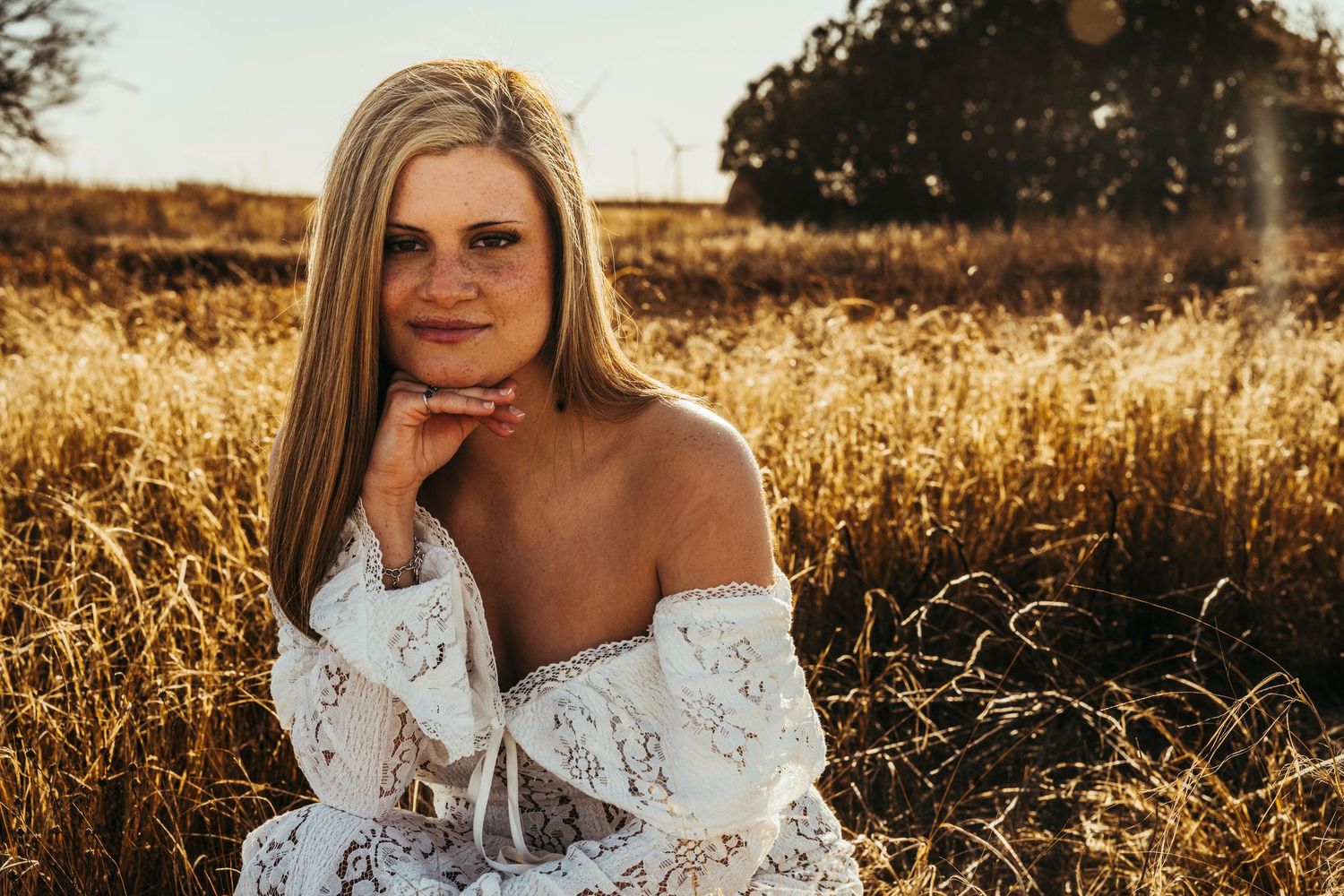 A dreamy golden hour photoshoot in a sun-drenched field with soft light and tall grass.