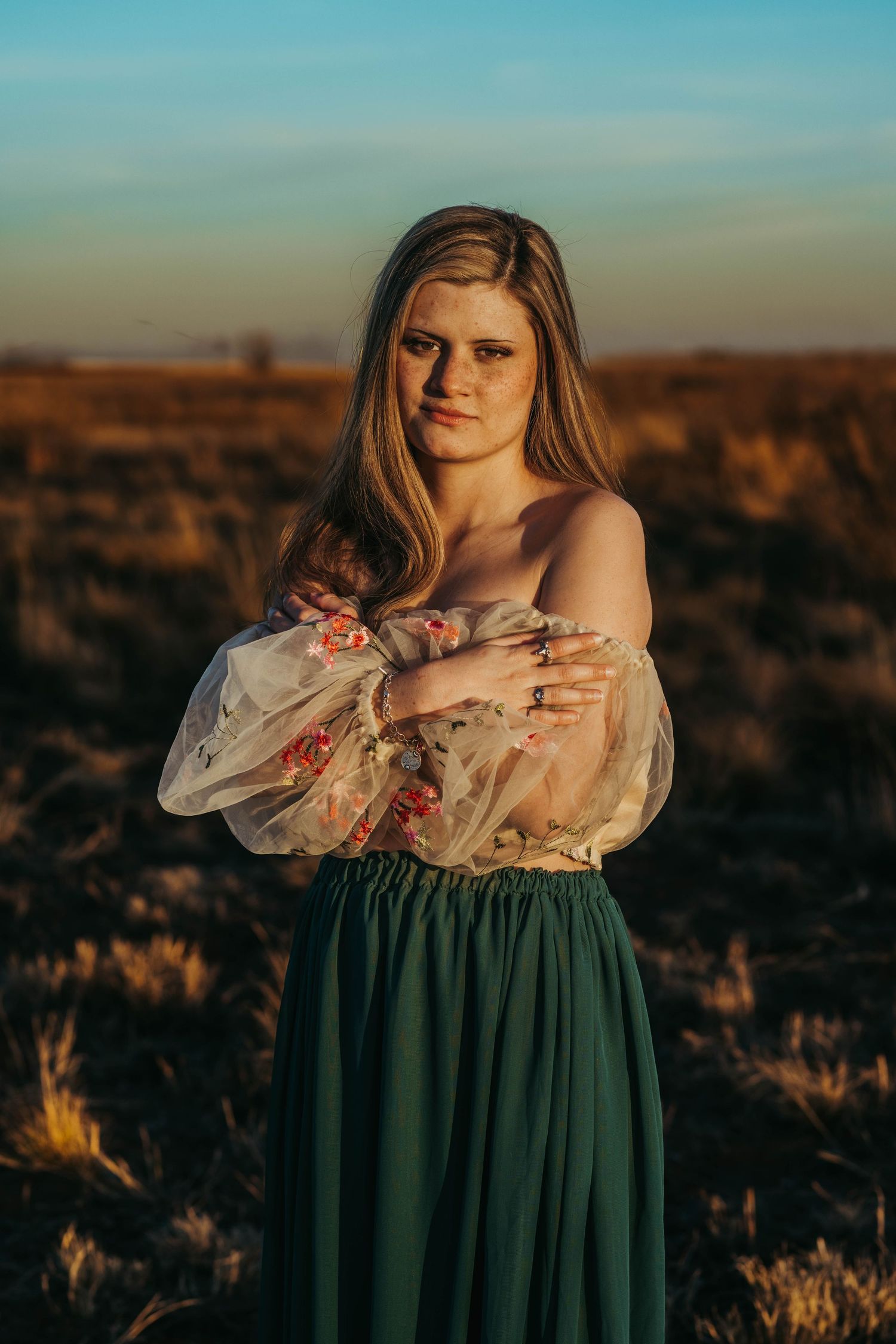 A figure in a vintage-style green dress poses against a desert landscape at golden hour.