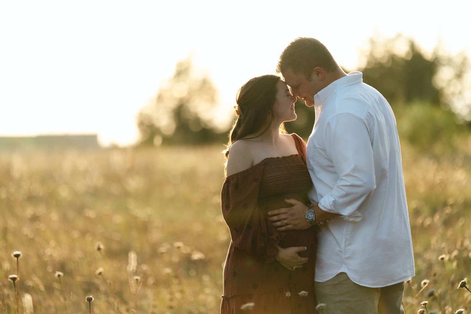Intimate moment captured between couple in a sun-drenched field.