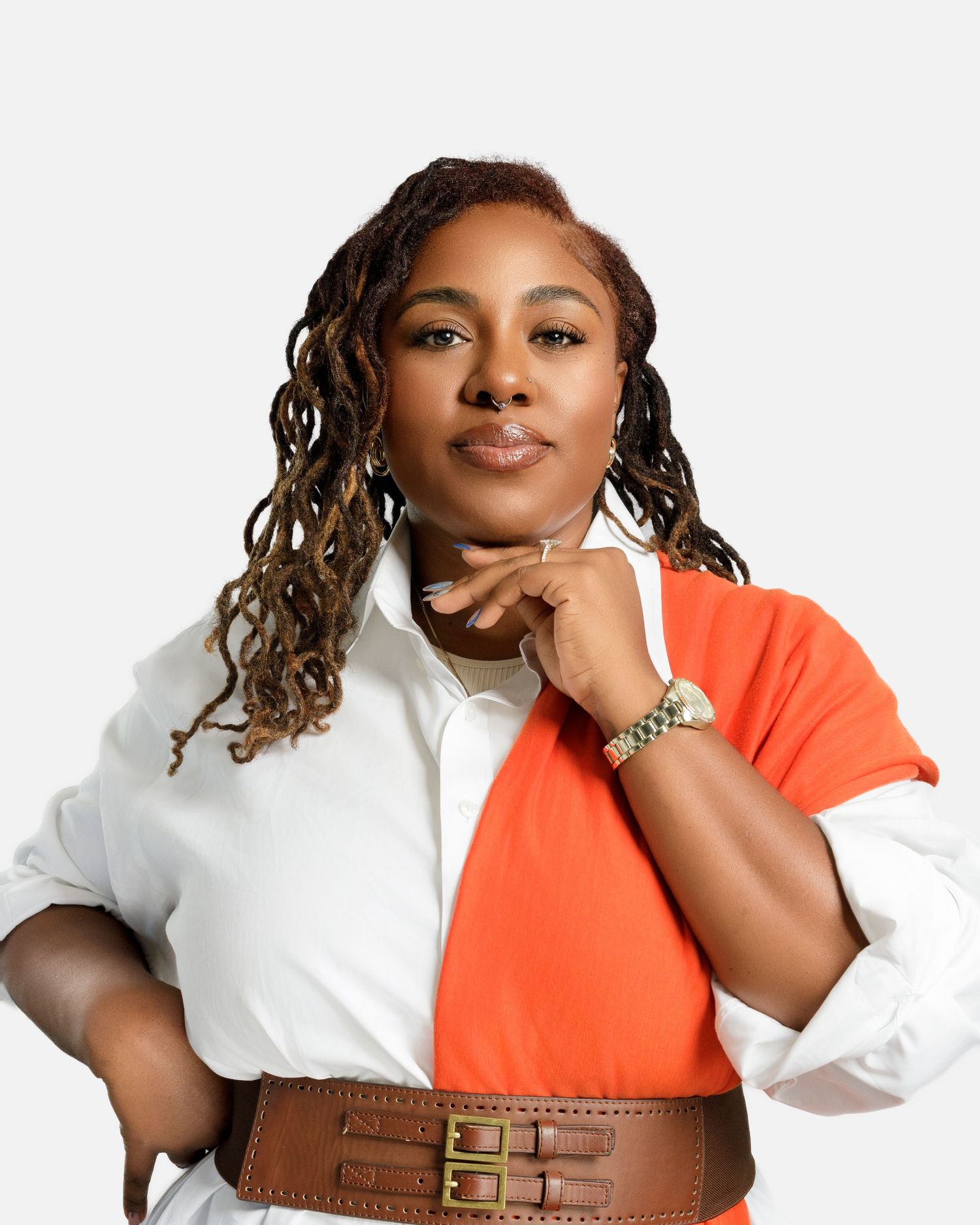 Business casual look with orange vest, white blouse and brown leather belt against white background.