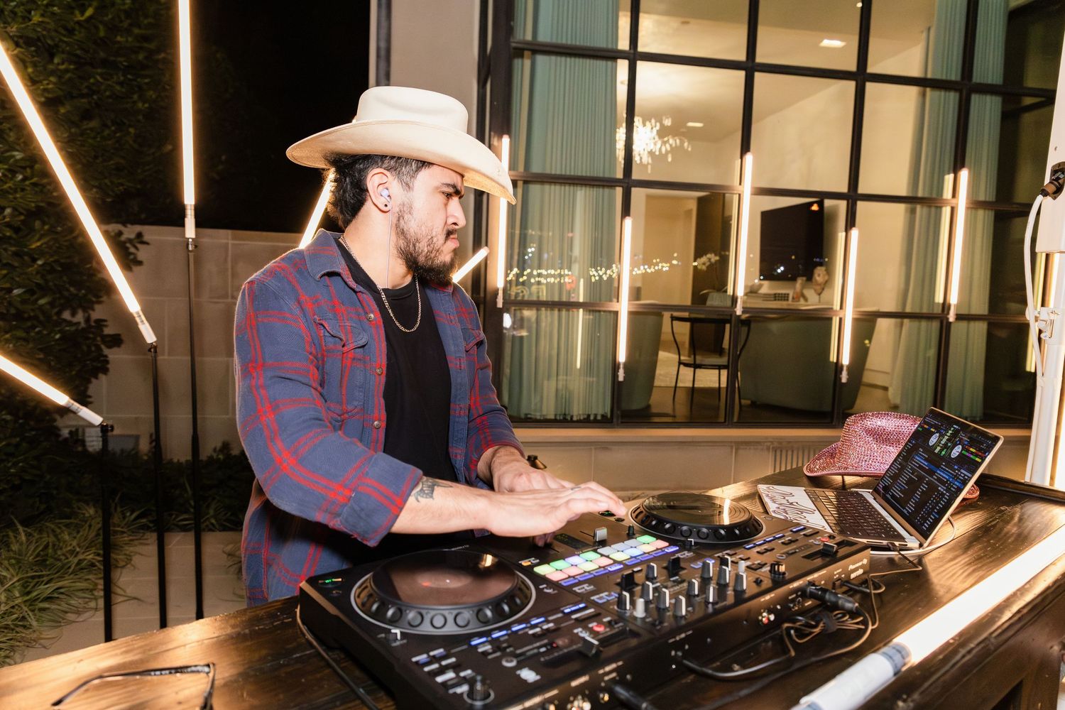 DJ mixing music at a modern venue with geometric LED light installations mounted on the wall.