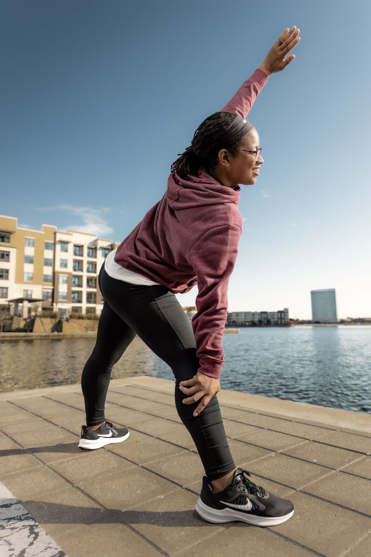 Series of stretching poses demonstrated on a waterfront boardwalk with urban buildings in background.