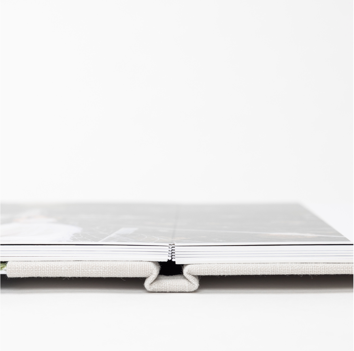 Three identical close-up views of a hardcover book binding showing white pages and spine details.
