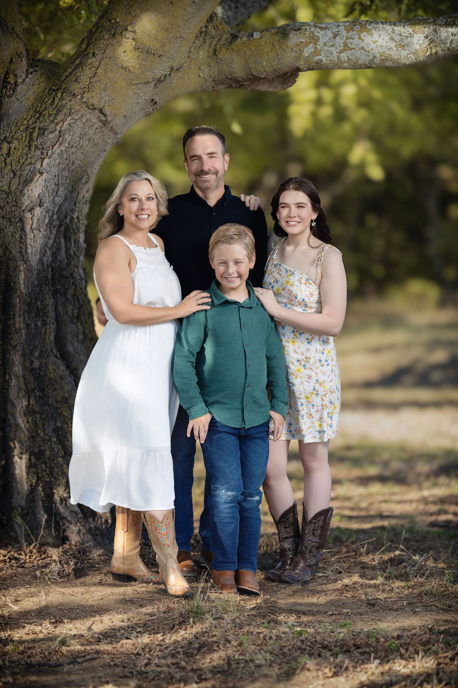 Four creative outdoor family portrait poses under a tree showing progression of revealing people from behind.