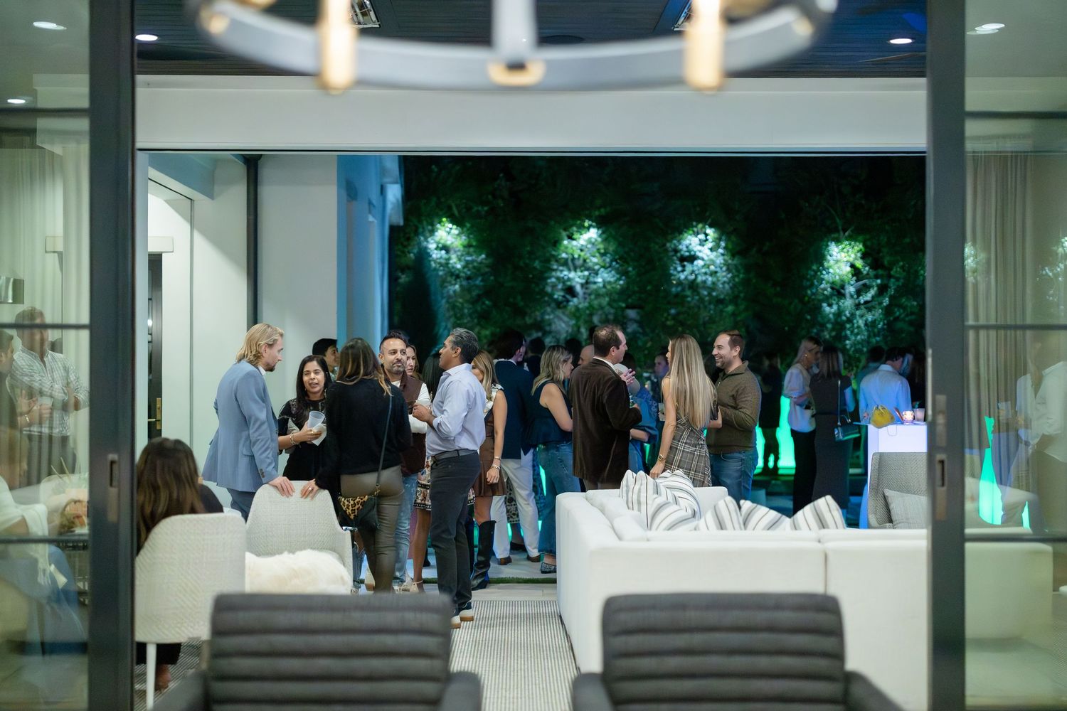 Evening reception guests mingle in a modern venue space with illuminated green wall decor.