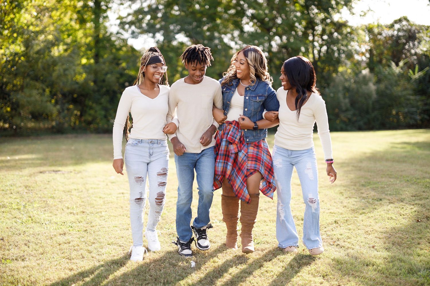Group walking together through a sunlit field wearing coordinated casual outfits.