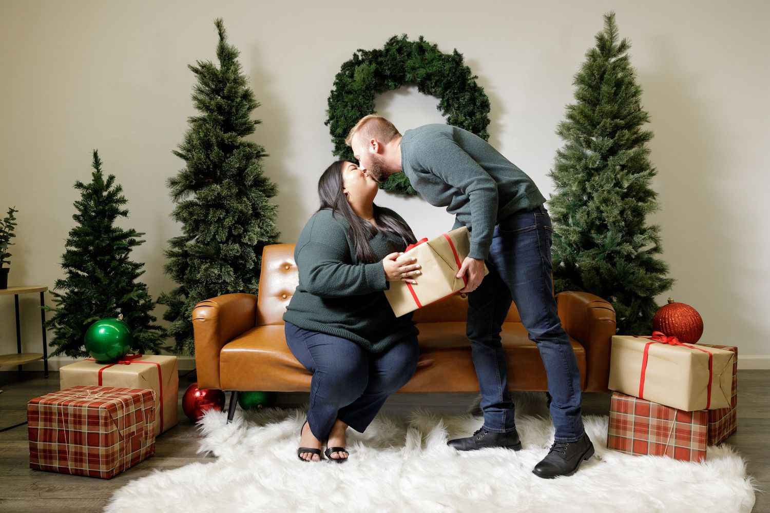 Holiday photography setup featuring wrapped gifts and evergreen trees against neutral backdrop.