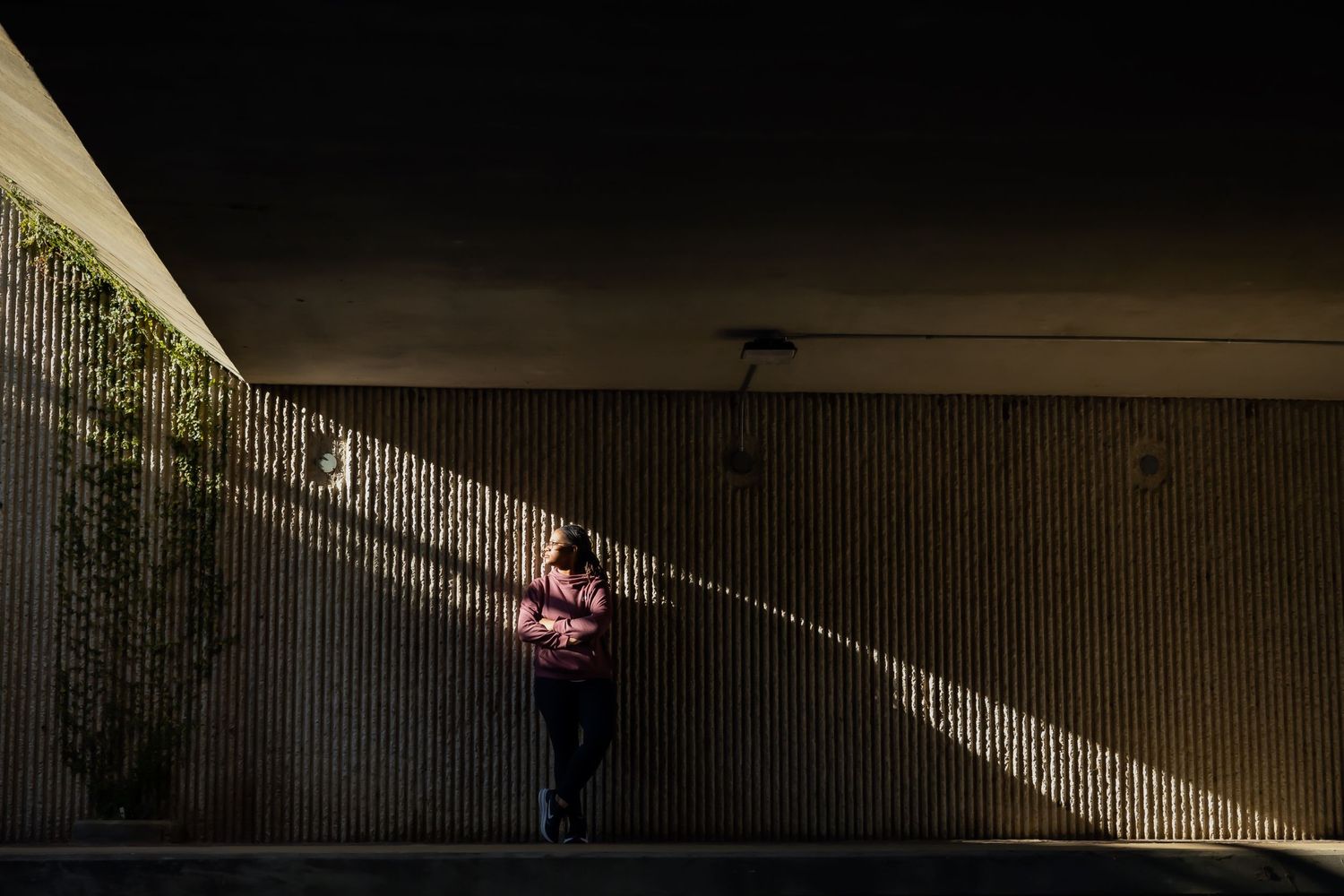 Dramatic shadows frame person performing parkour moves in architectural setting.